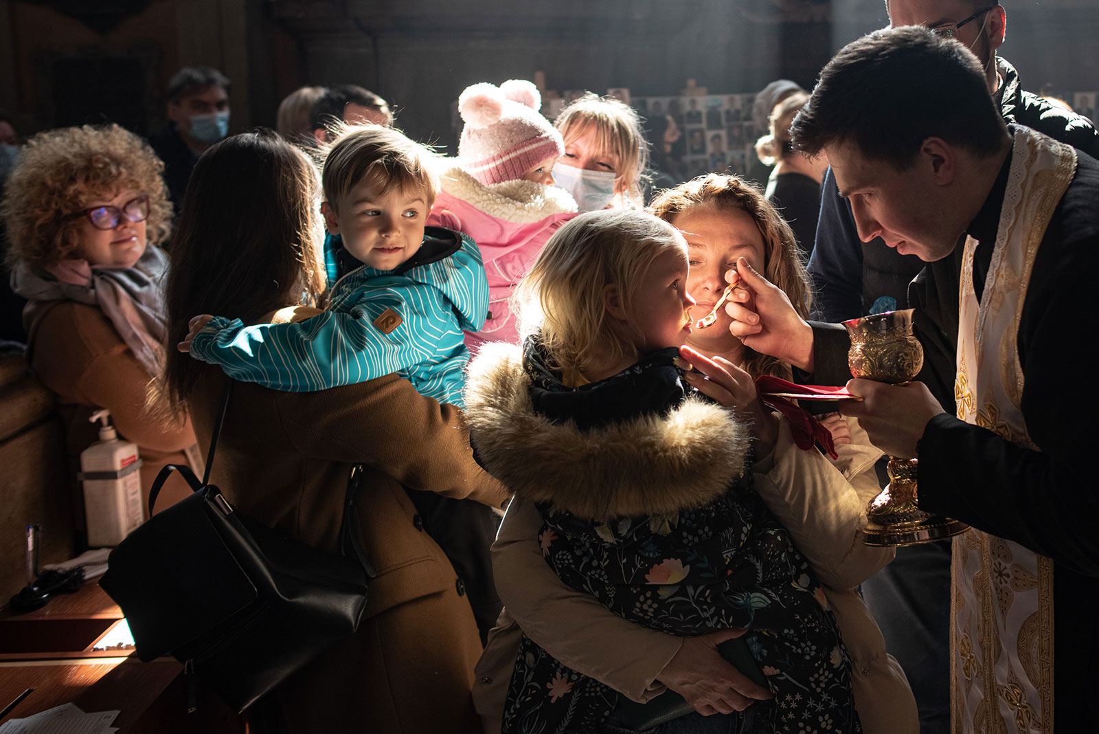 A girl receives communion during a church service at Saints Peter and Paul Garrison Church on Sunday, March 20 in Lviv, Ukraine. The city has served as a stopover and shelter for the millions of Ukrainians fleeing the Russian invasion. 