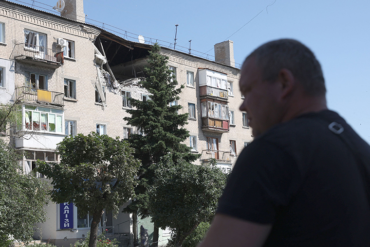 A man walks in front of damaged residential building on a street of the town of Lysychansk on June 21.