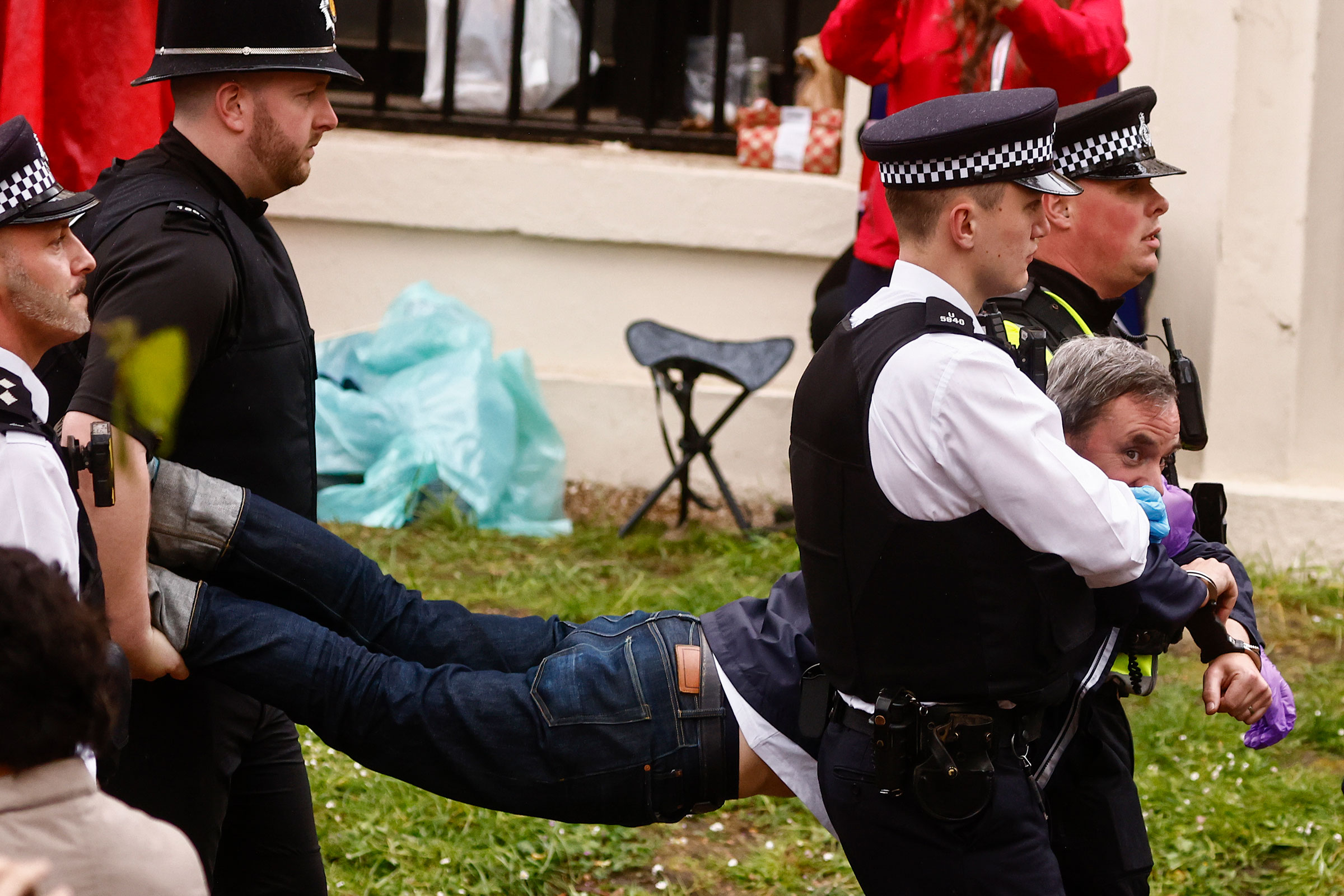 Police officers detain a member of the "Just Stop Oil" movement as people gather to watch the procession during the Coronation of King Charles III and Queen Camilla on Saturday in London.