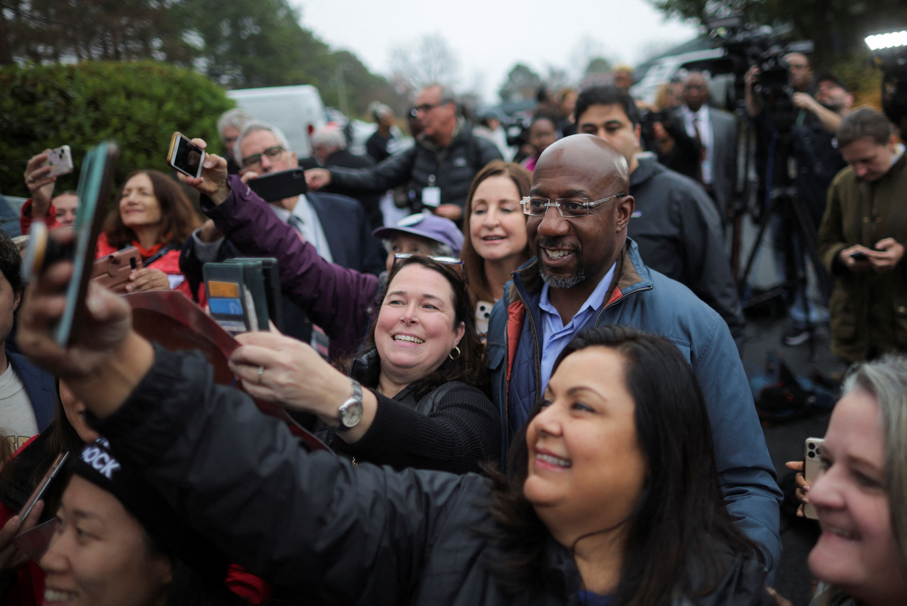 Sen. Raphael Warnock poses for a picture with supporters during a visit at a campaign office in Norcross, Georgia, on Tuesday.