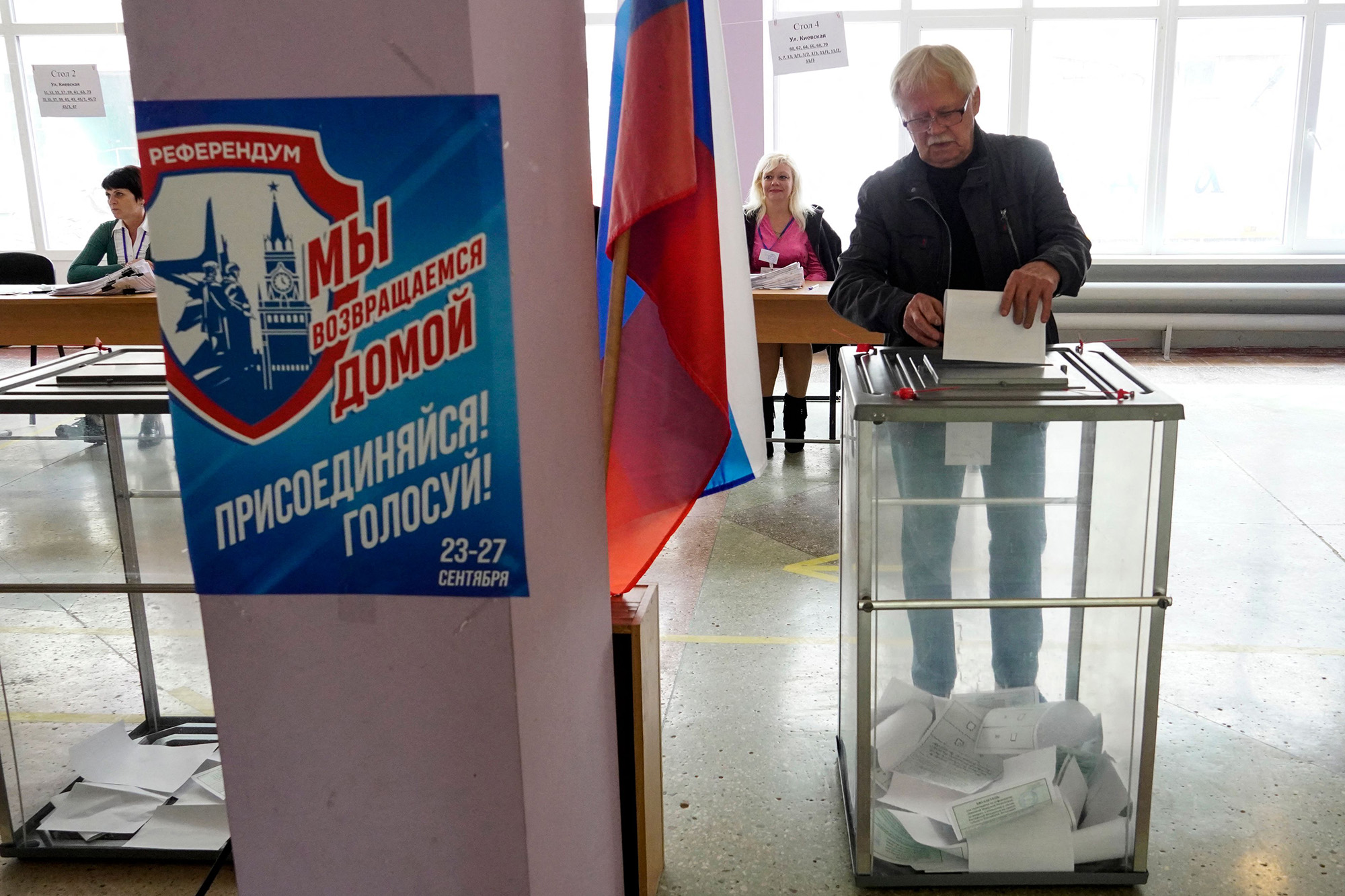 A man casts his ballot for a referendum at a polling station in Mariupol on September 27. The placard reads "Referendum. We are returning home. Join! Vote!". 