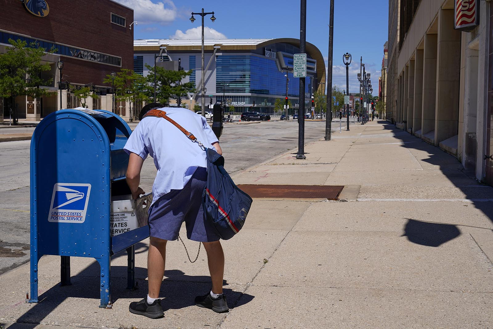 A postal worker empties a box near the Fiserv Forum on Tuesday, Aug. 18, in Milwaukee.