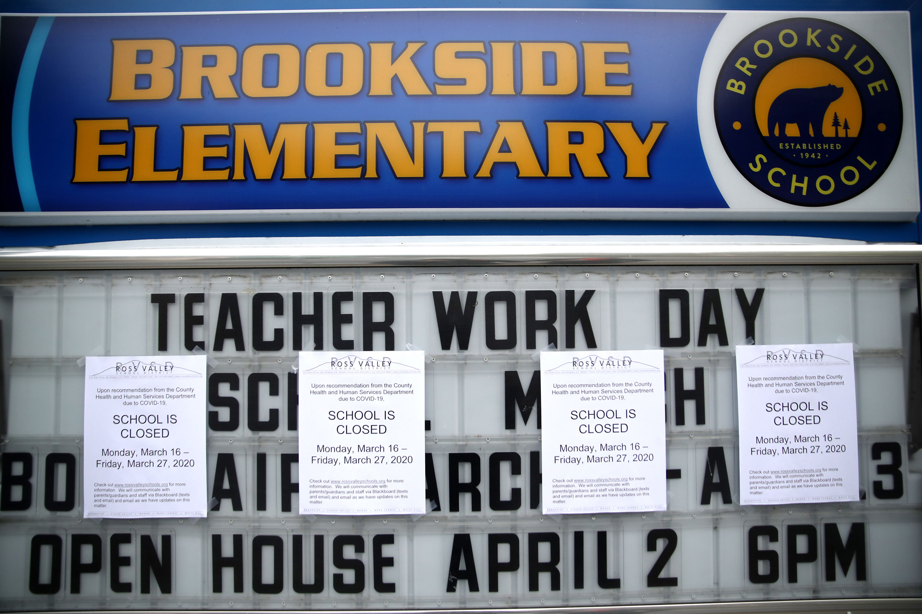 A message board outside of Brookside Elementary school is covered over with signs announcing the school's closure on March 17 in San Anselmo, California.