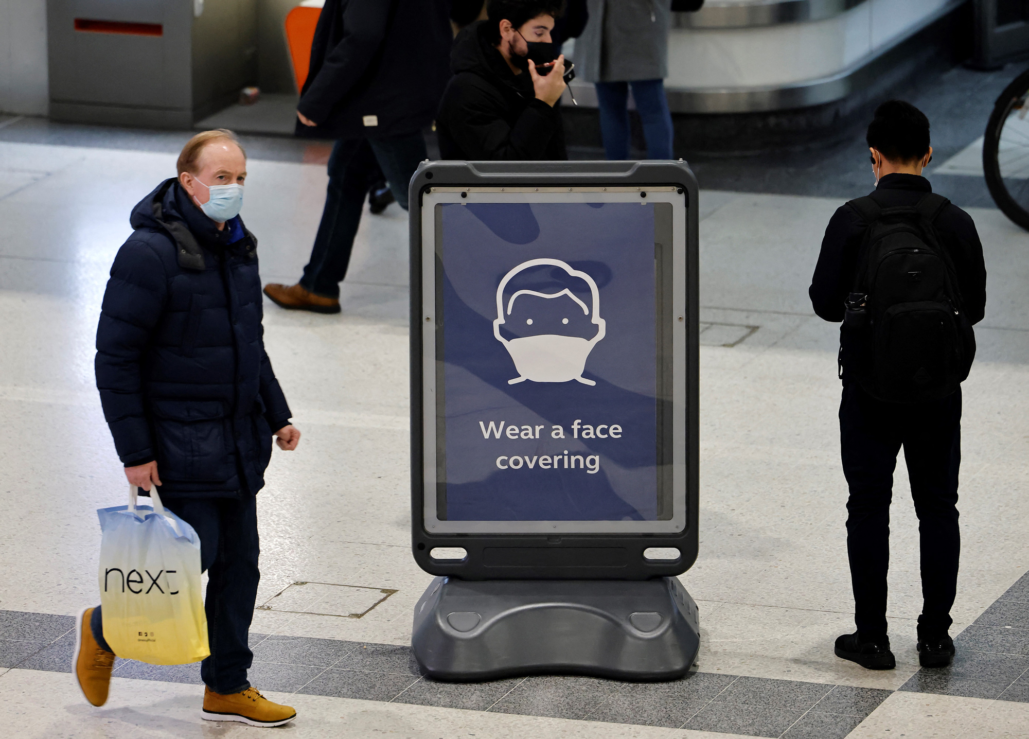 Pedestrians walk past a sign at Liverpool Street train station in London on December 18.
