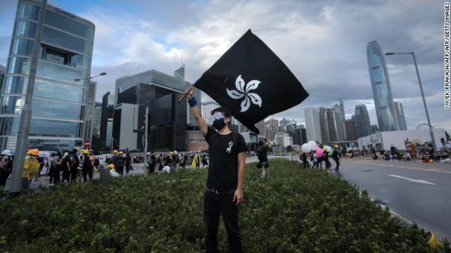 A protester waves a "black bauhinia" flag as others set up barricades outside the Legislative Council in Hong Kong before the flag-raising ceremony on July 1, 2019. 