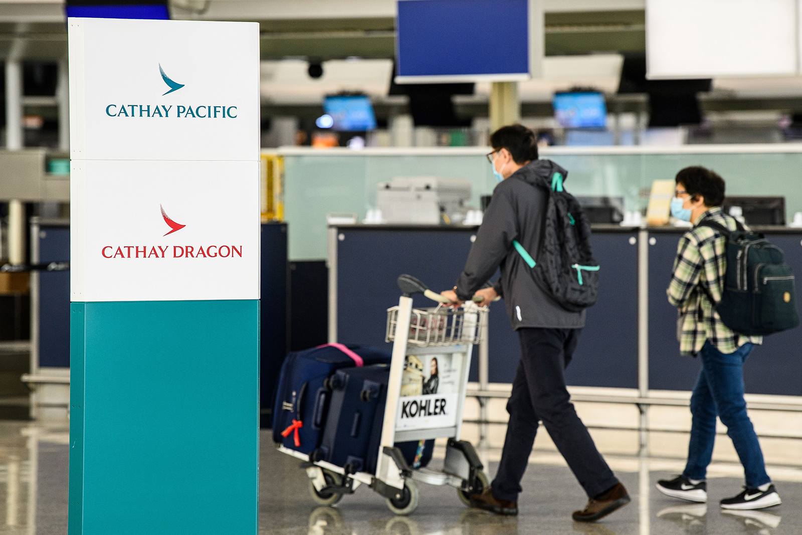 Passengers walk past signage for Cathay Pacific and Cathay Dragon near the city's flagship carrier check-in counters at Hong Kong International Airport, on October 20.