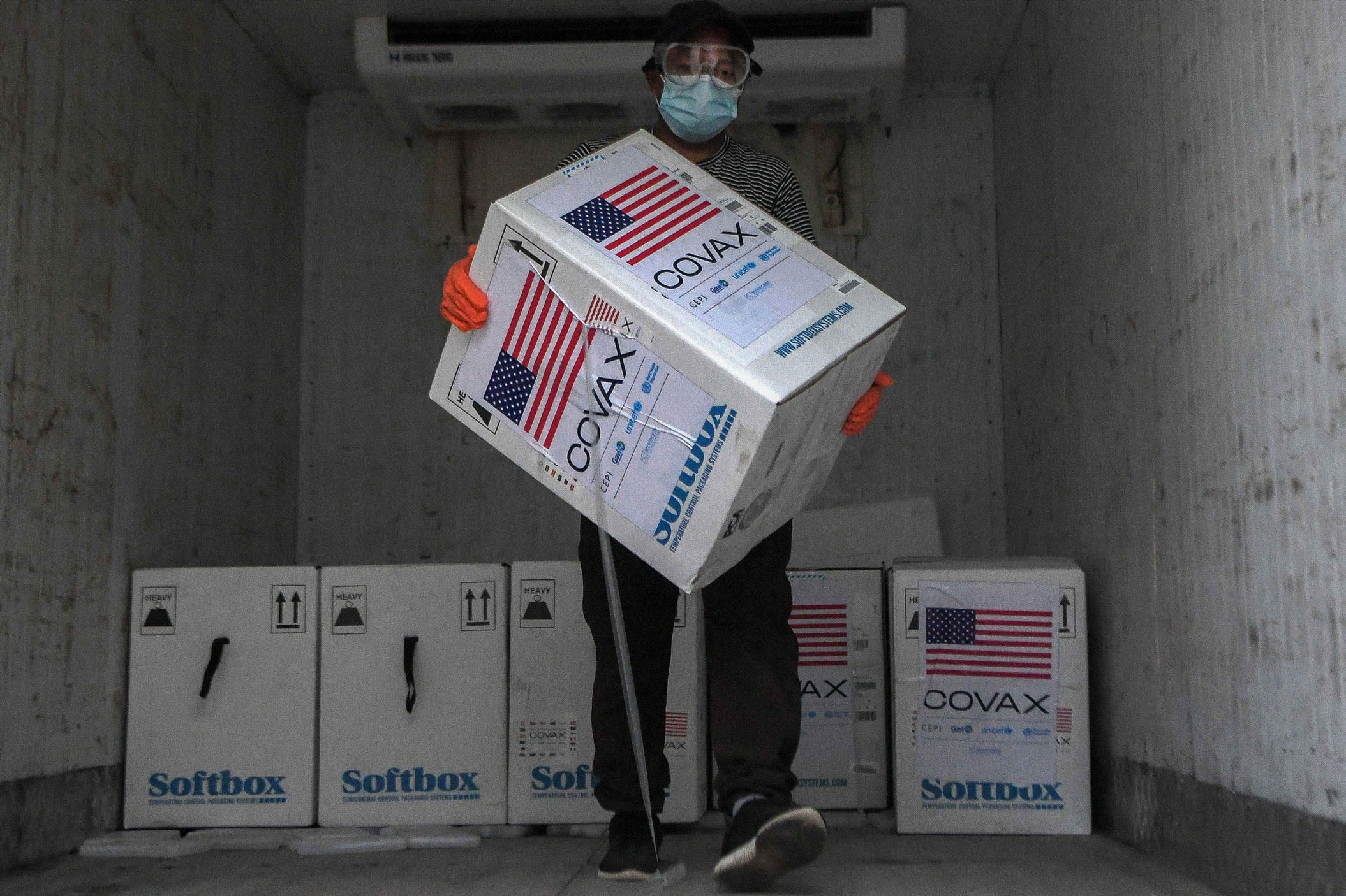 A worker unloads boxes from the consignment of the Pfizer-BioNTech vaccines against the Covid-19 Coronavirus donated to Nepal by the US government at a cold storage facility in Kathmandu on October 25, 2021