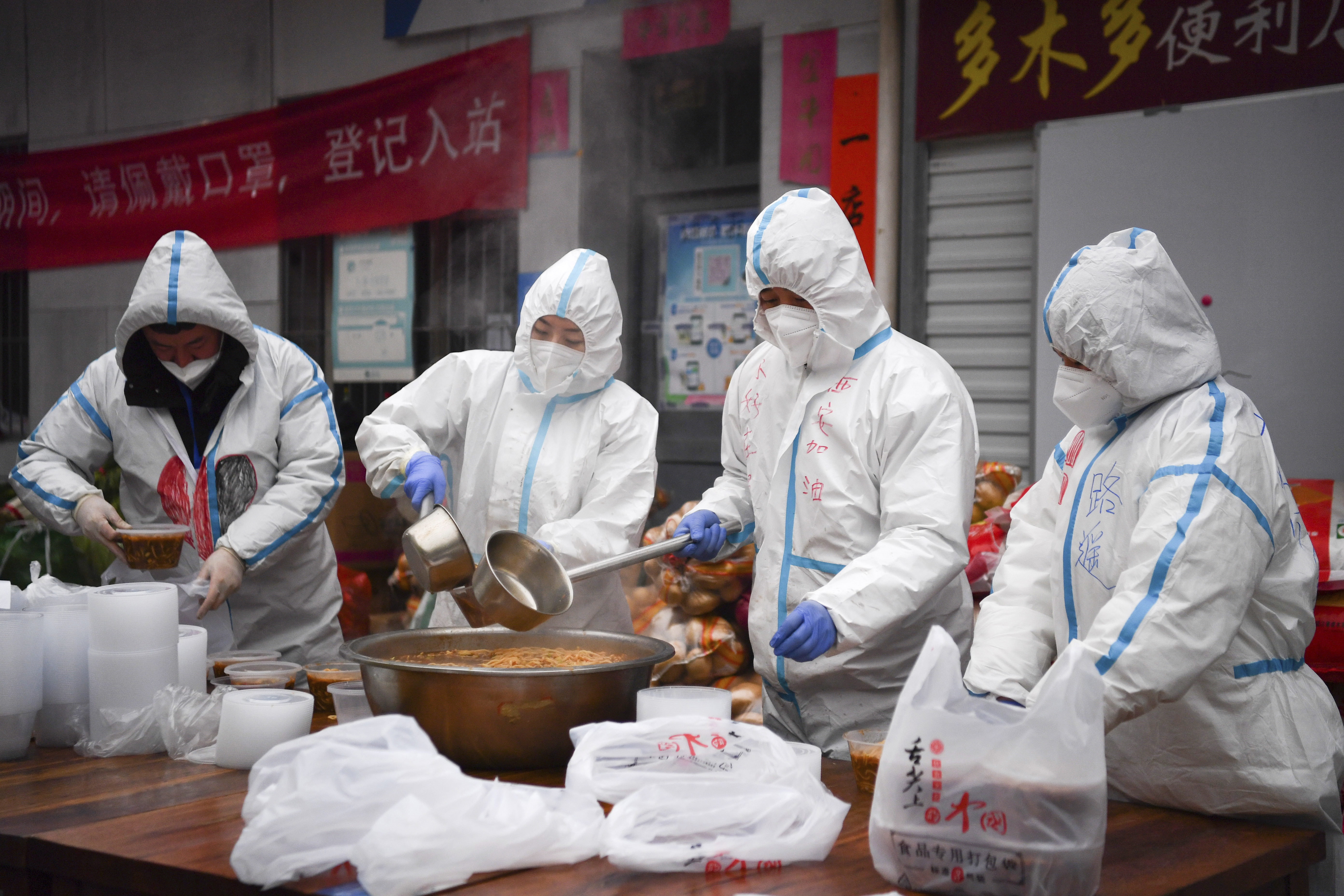 In this photo released by China's Xinhua News Agency, volunteers wearing protective suits package meals for delivery to people under lockdown in Xi'an in northwestern China's Shaanxi Province, Tuesday, January. 4, 2022. Hospital officials in the northern Chinese city of Xi'an have been punished after a pregnant woman miscarried after being refused entry, reportedly for not having current COVID-19 test results. 