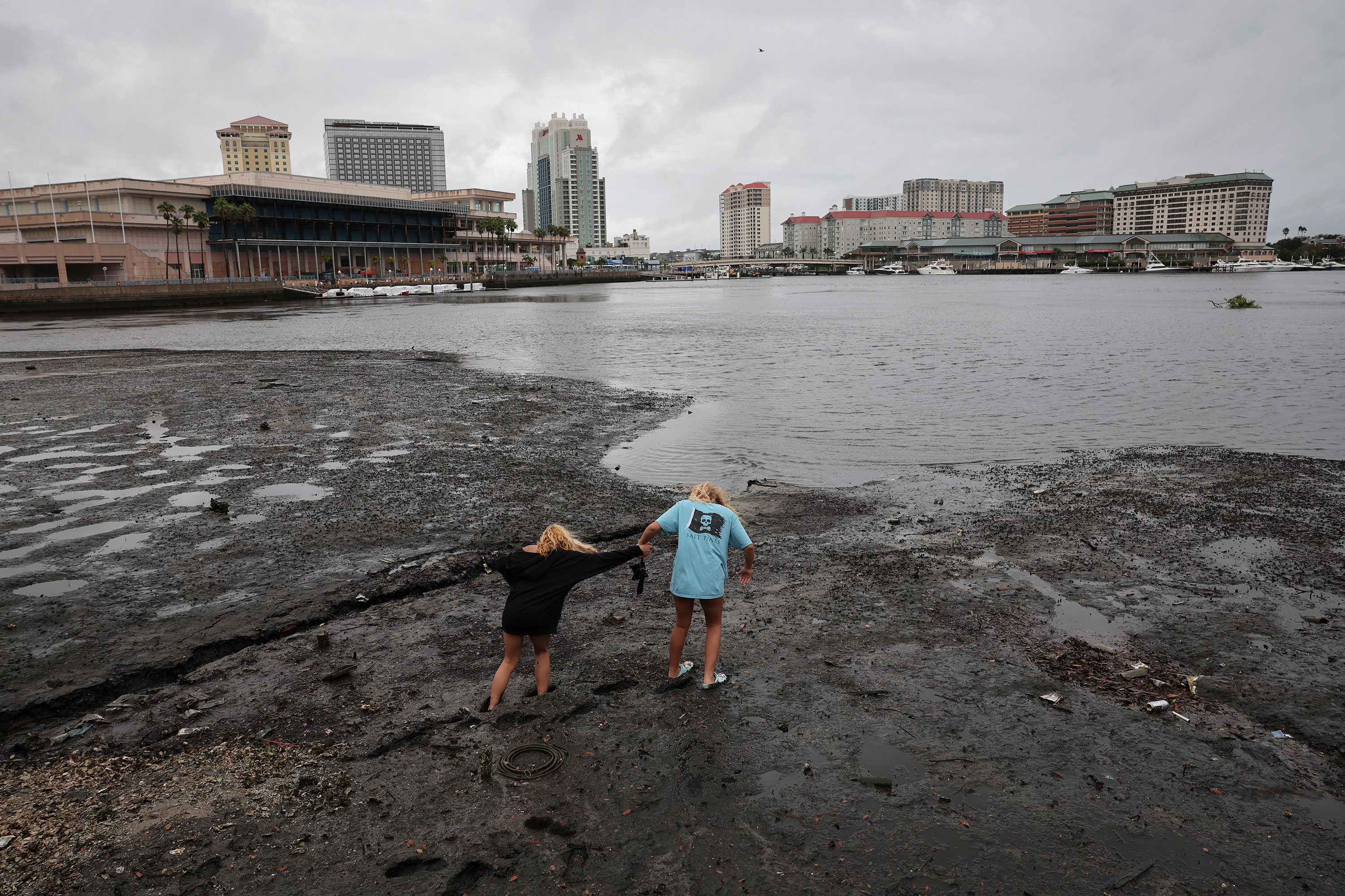 Sisters Selena Disbrow, left, Angel Disbrow, right, walk along the shore of Tampa Bay as water is pulled out from the bay by Hurricane Ian on Wednesday.