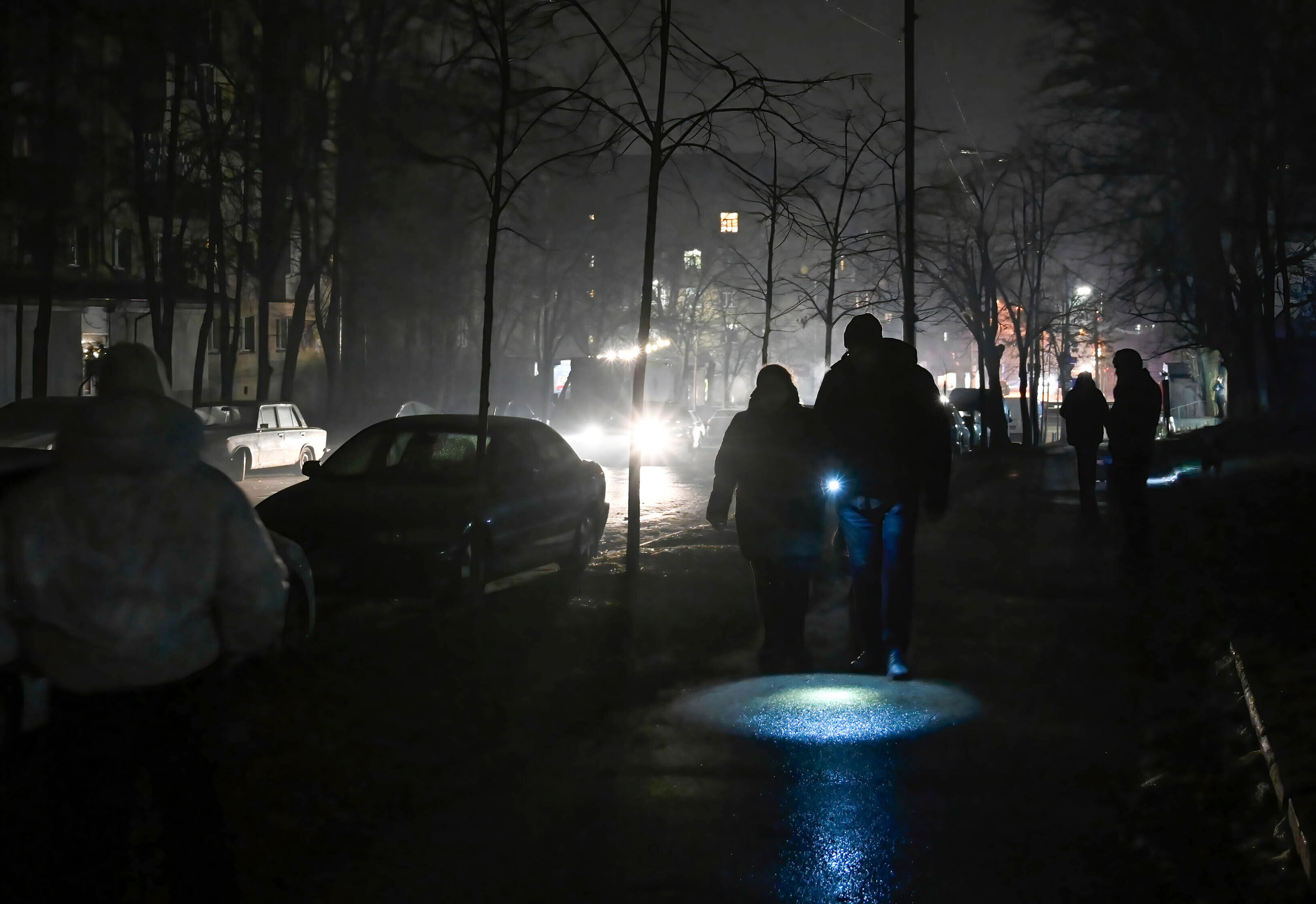 People use flashlights as they walk on a dark street during a blackout in Kyiv, Ukraine, on December 24. 