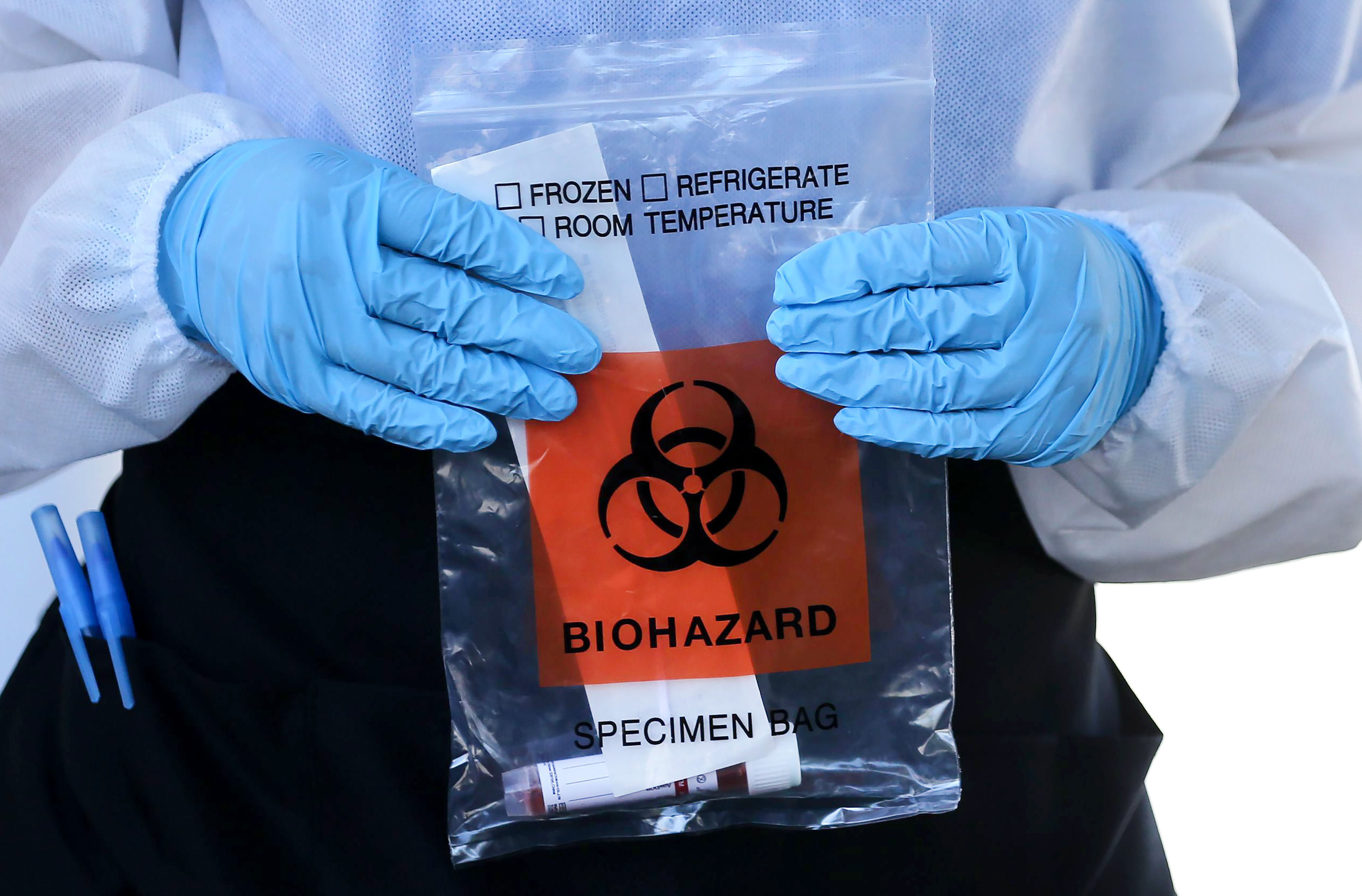 A health care worker in Los Angeles carries a kit at a drive-in Covid-19 testing center on August 11.