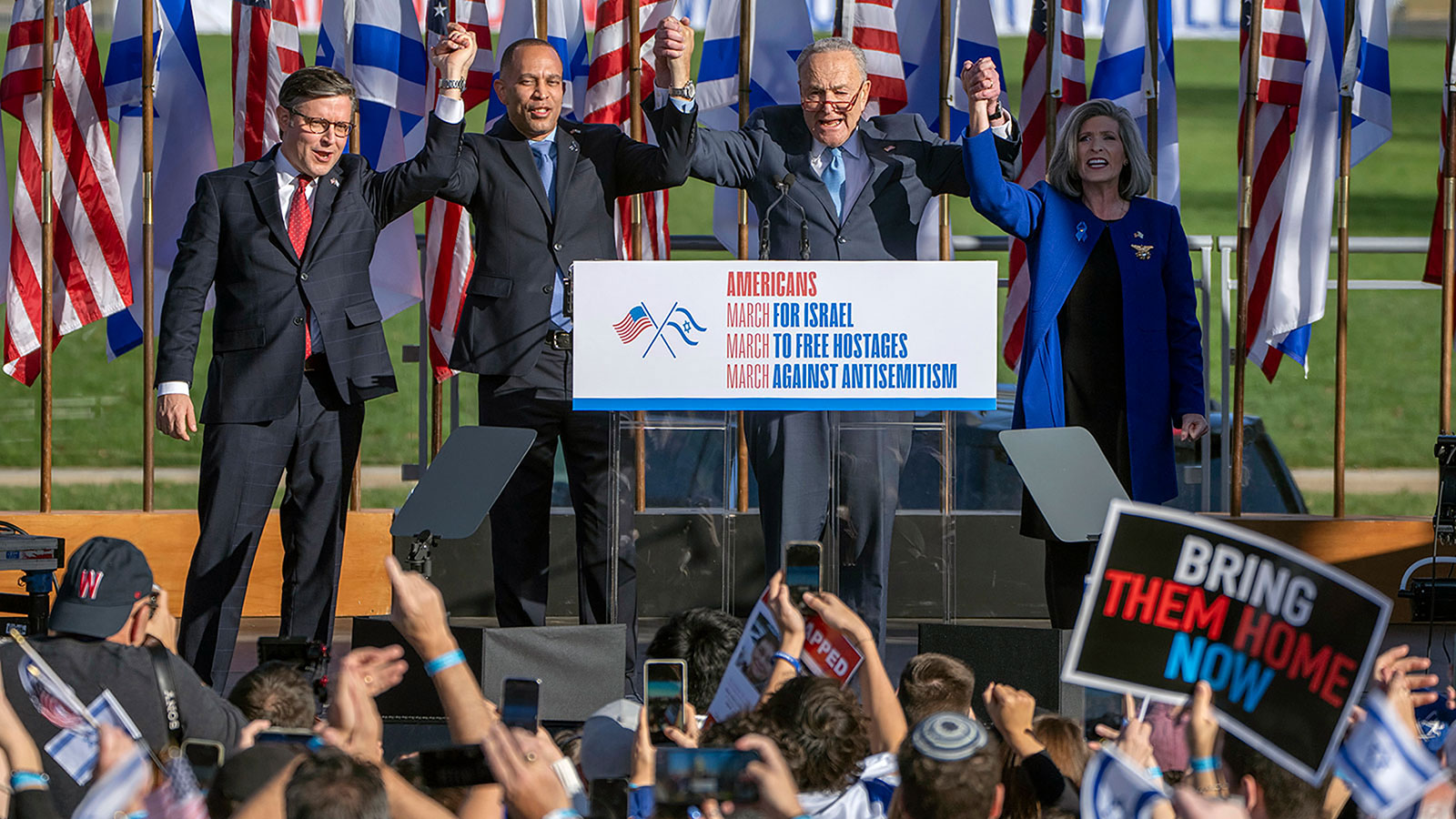 From left, Speaker of the House Mike Johnson, House Minority Leader Hakeem Jeffries, Senate Majority Leader Chuck Schumer and Sen. Joni Erns  join hands at the March for Israel on Tuesday, November 14, on the National Mall in Washington., DC. 