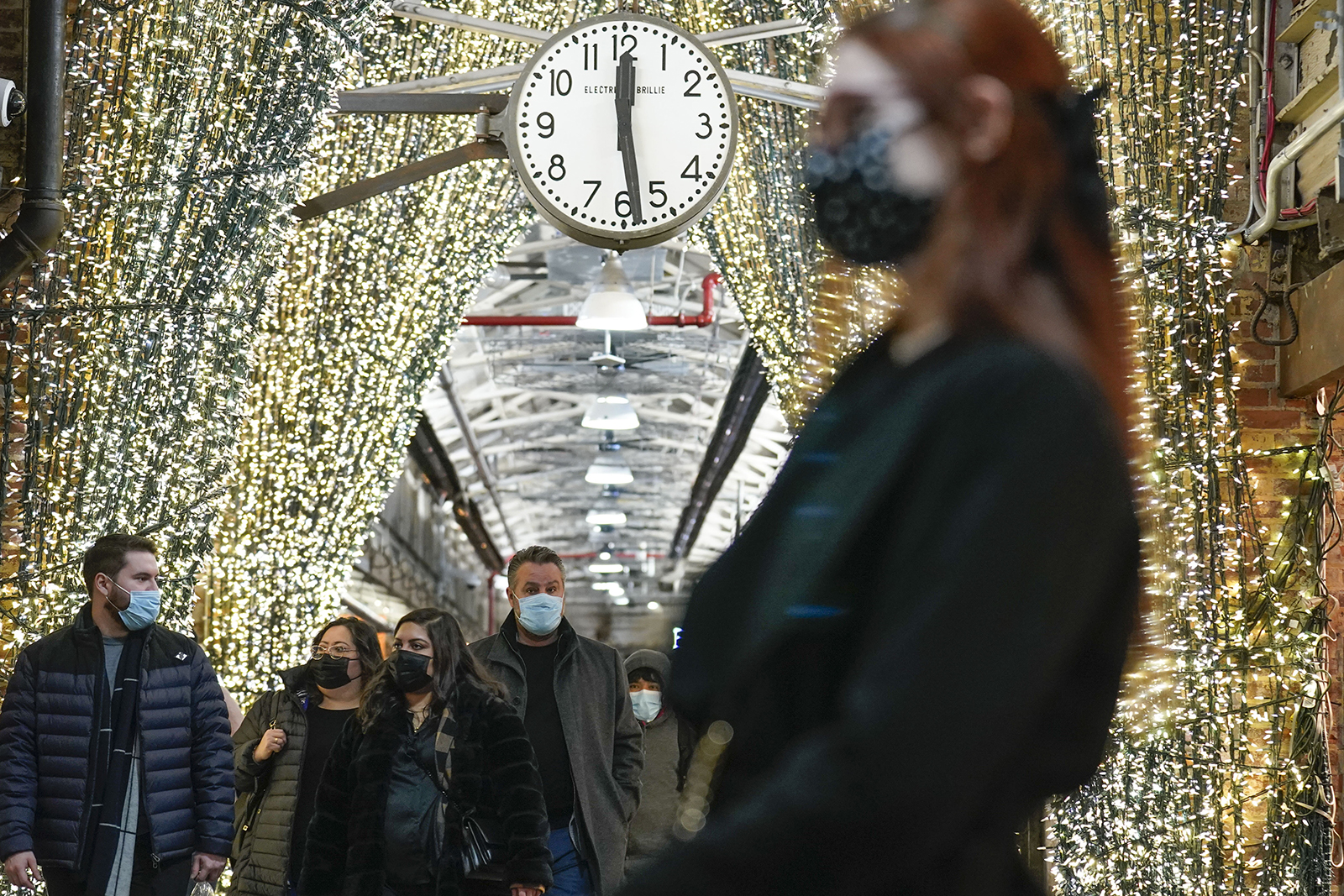 Shoppers wear masks while walking through an indoor market in New York, on Wednesday, Feb. 9.