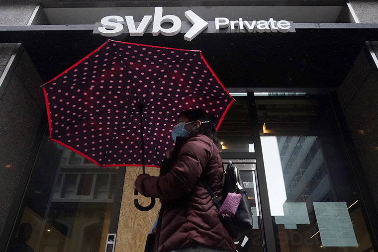 A pedestrian carries an umbrella while walking past a Silicon Valley Bank Private branch in San Francisco, on March 14.