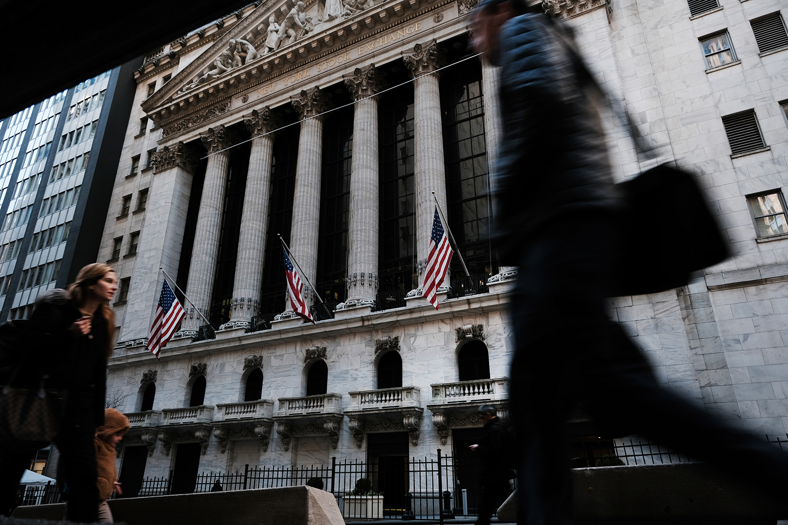 People walk by the New York Stock Exchange today in New York City. 