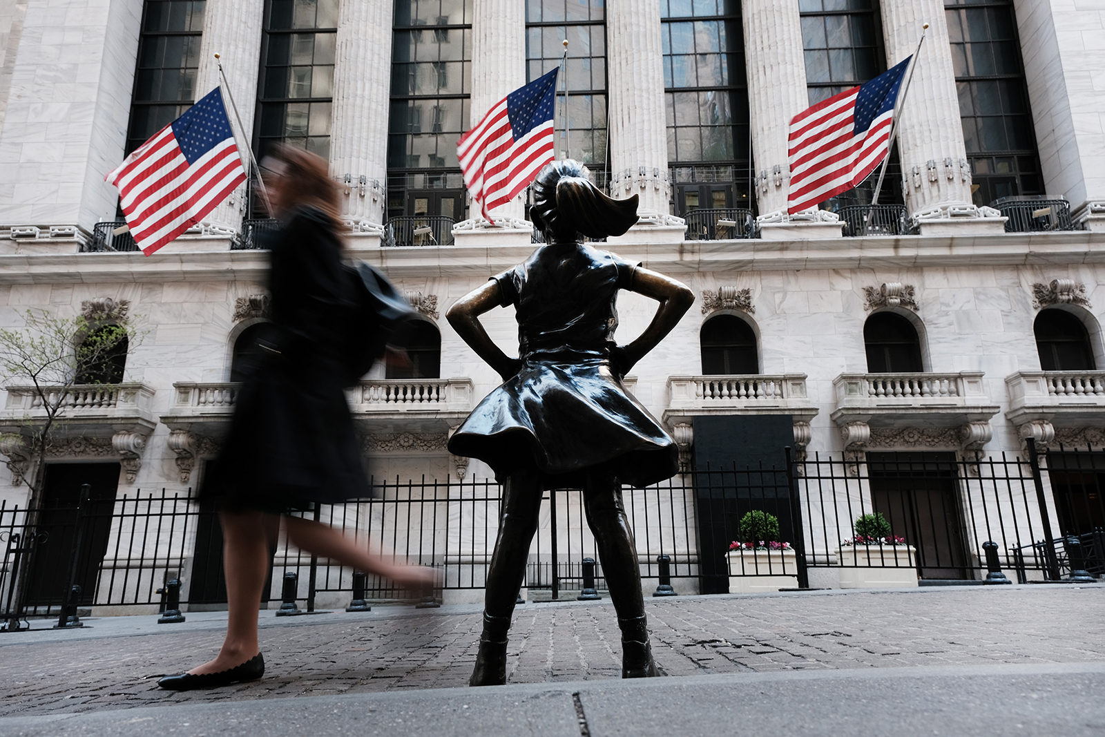 People walk by the bronze sculpture 'Fearless Girl' outside of the New York Stock Exchange (NYSE) on April 21 in New York City.