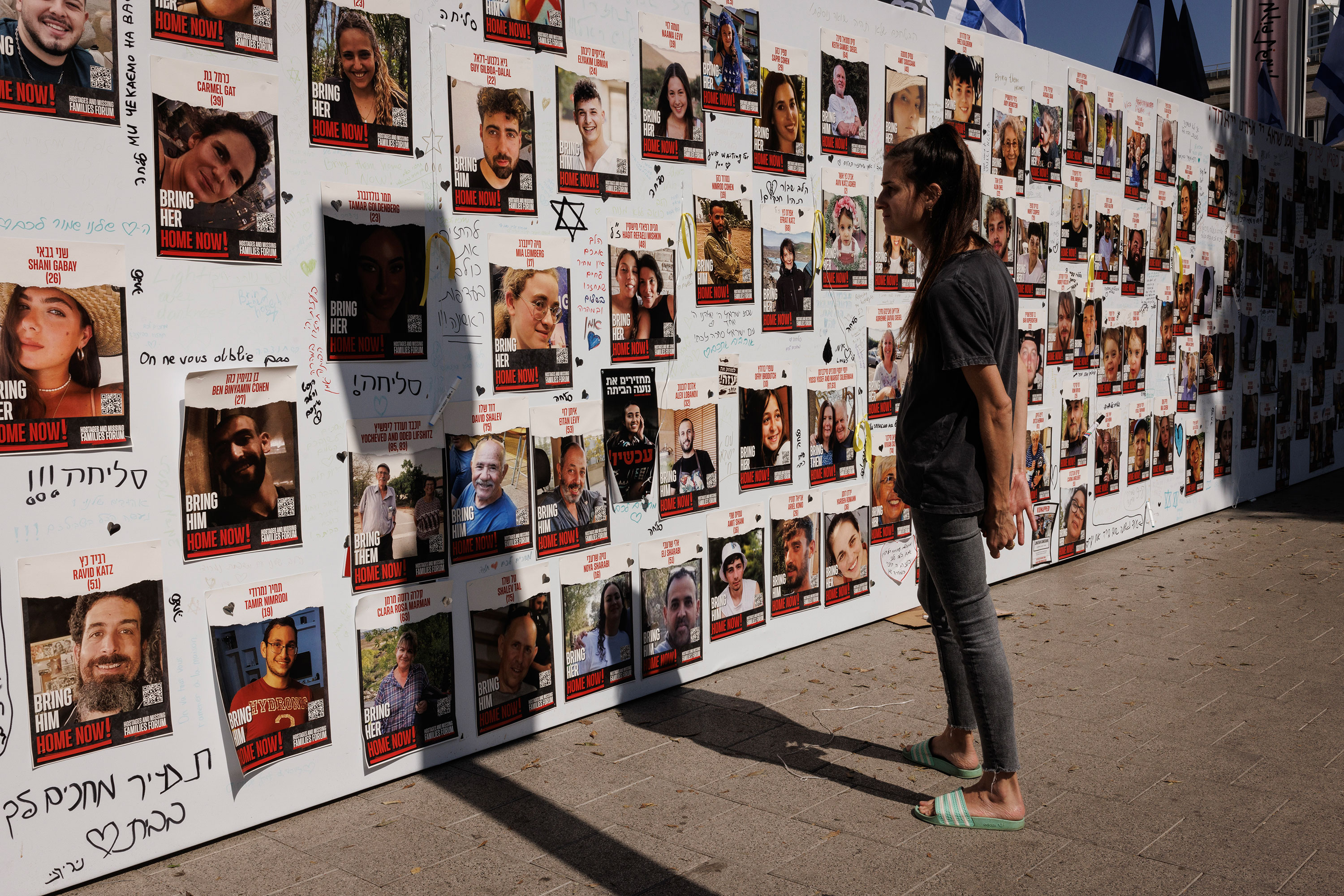 A woman looks at a wall in Tel Aviv, Israel, displaying pictures of people held hostage on October 26. 