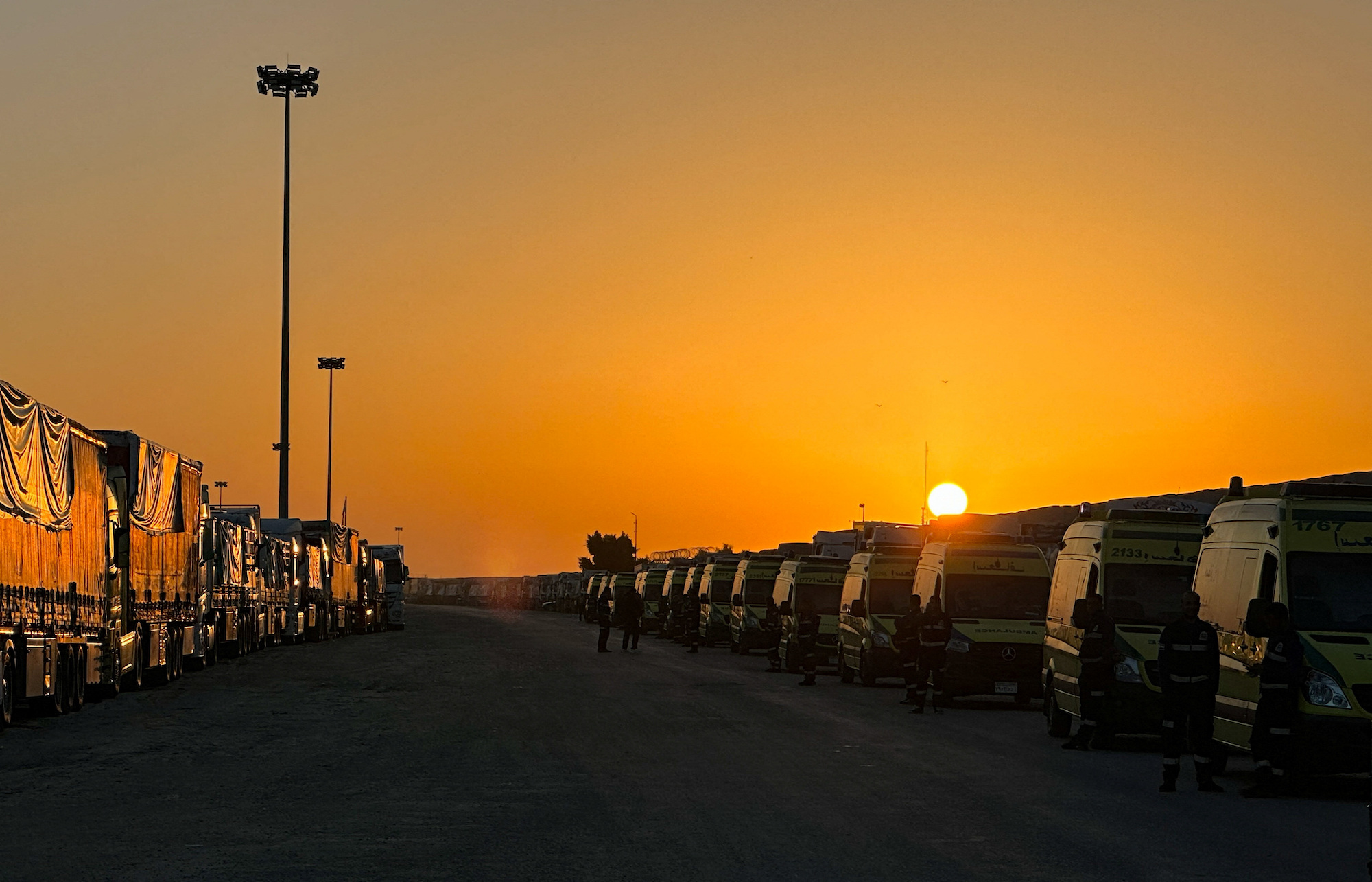 People stand next to ambulances and trucks with aid as they wait to enter Gaza from Rafah, Egypt on December 11.