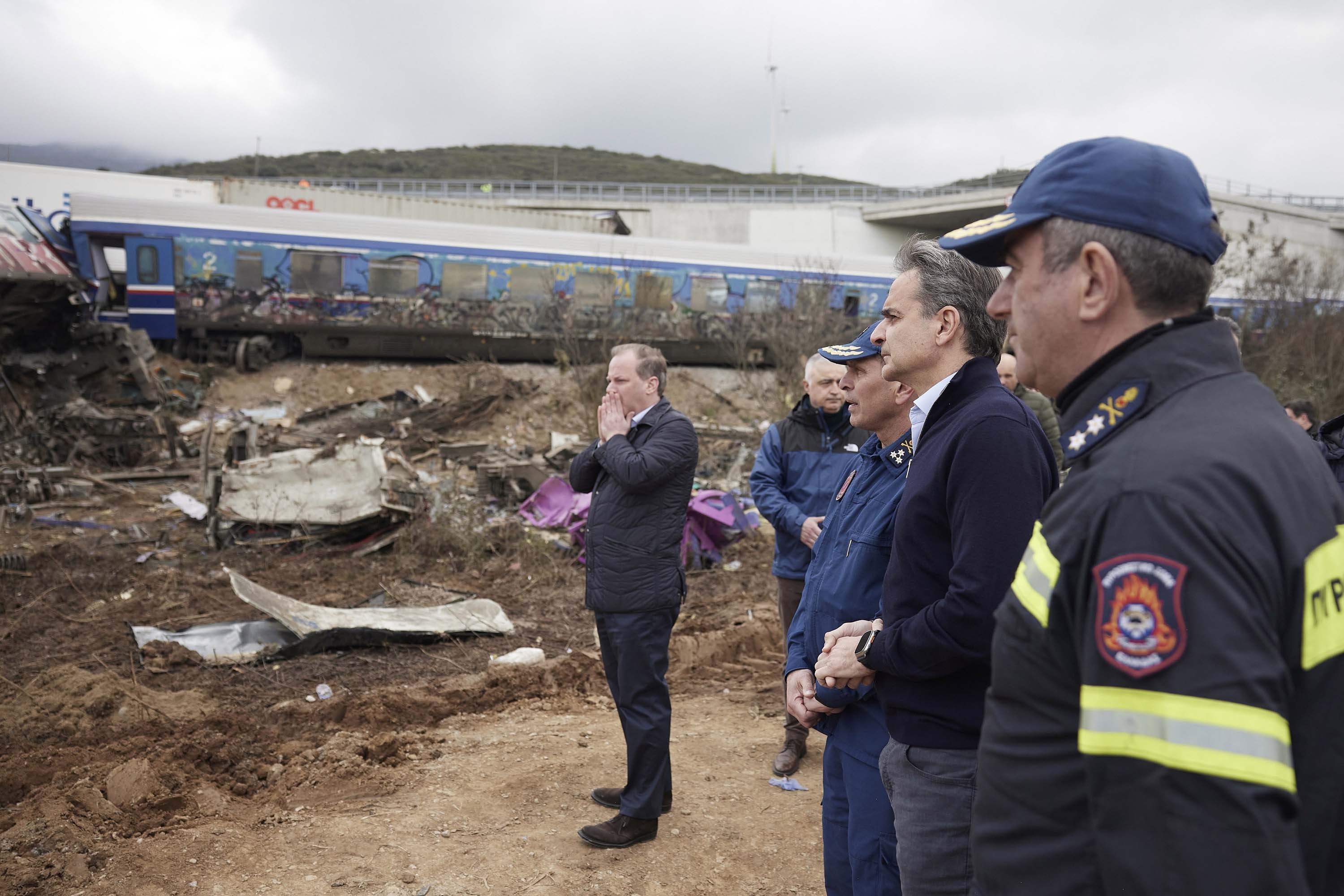 Greek transport minister Kostas Karamanlis, center, views the aftermath of the train collision, along with Greece's Prime Minister, Kyriakos Mitsotakis, second right, in Tempi, Greece, on Wednesday.