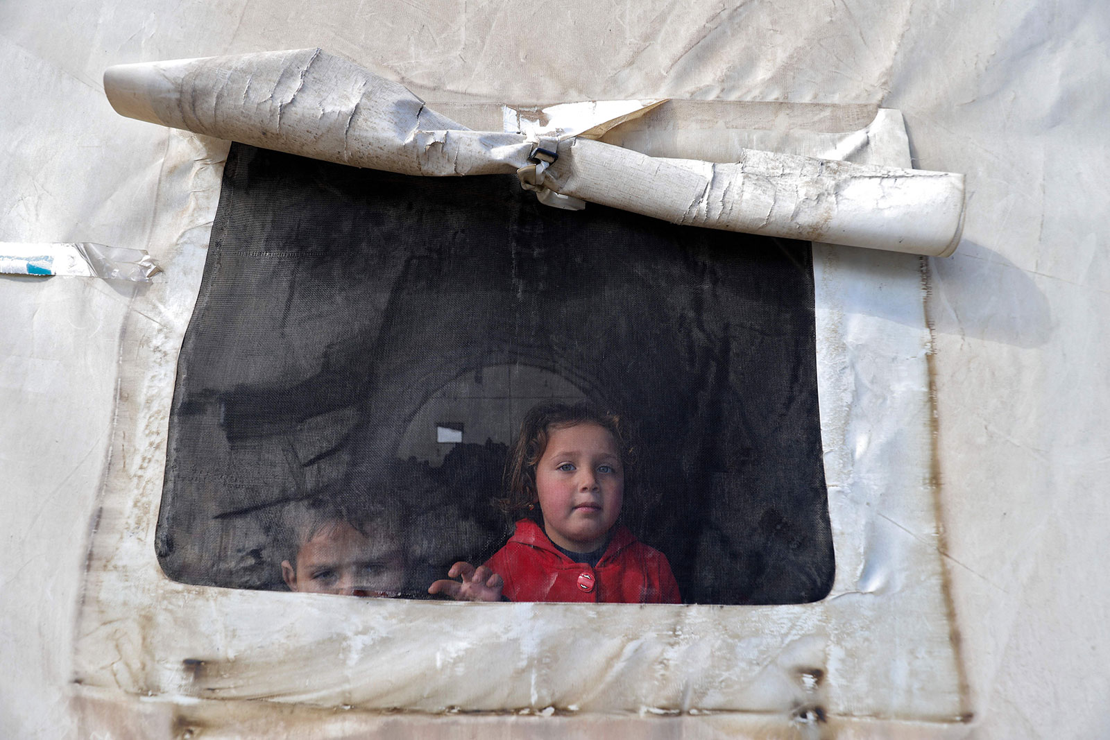 Syrian children look out of the window of a tent at an emergency shelter in the northwestern Idlib province of Syria on February 7.  