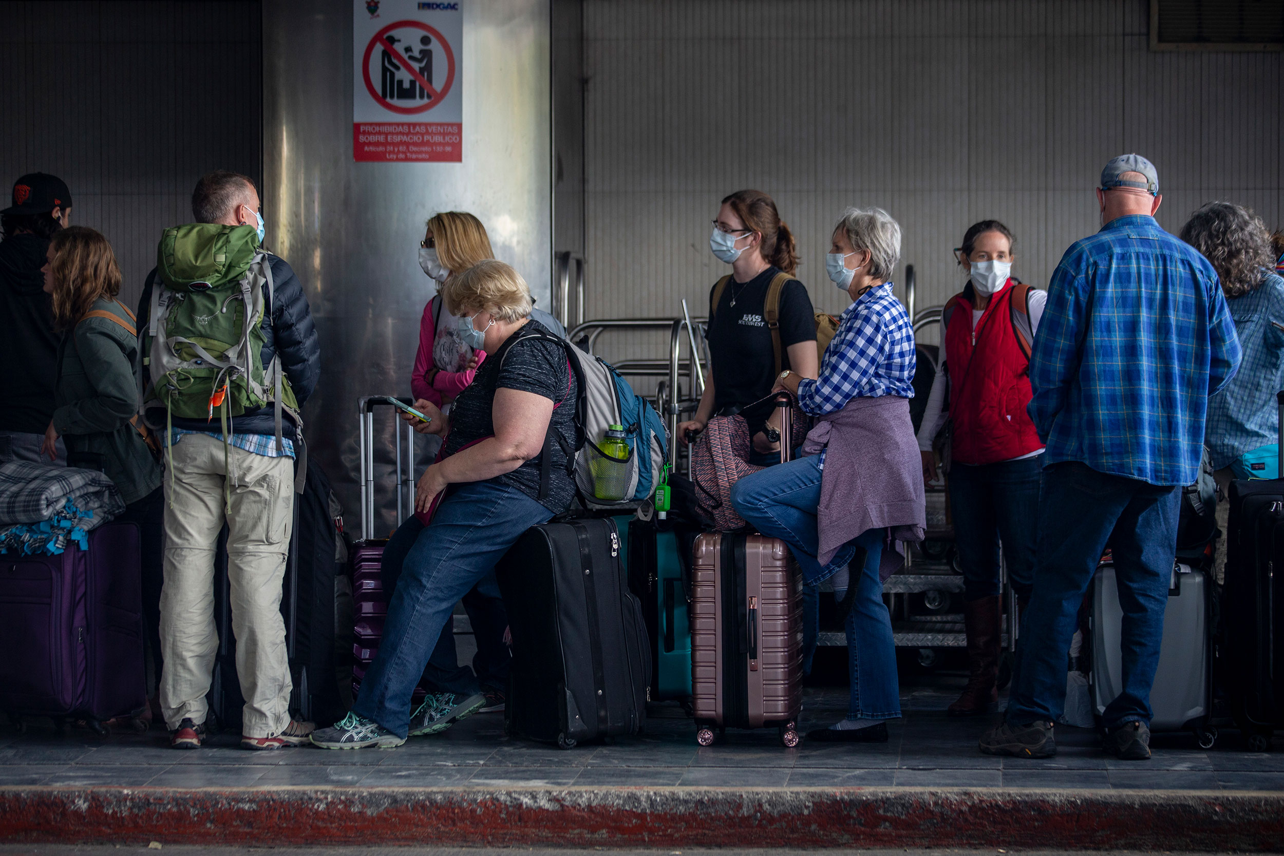 Travelers wait in line for a charter flight back to the United States at La Aurora International Airport in Guatemala on Monday, March 23.