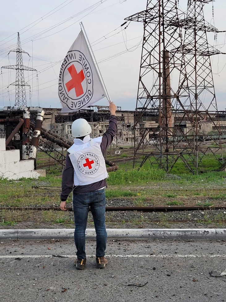 In this image provided by the International Committee of the Red Cross, a Red Cross official waves a white flag while approaching the Azovstal steelworks in Mariupol, Sunday.