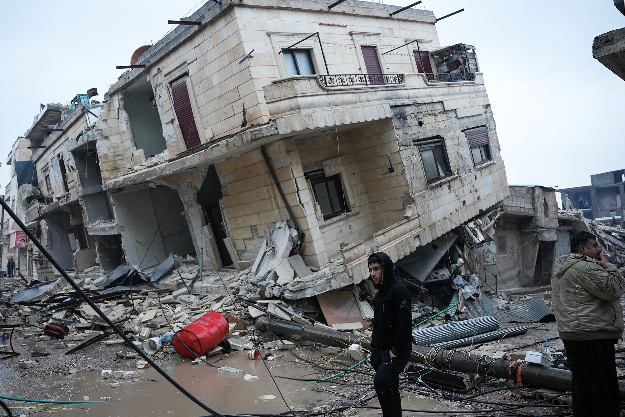Residents stand in front of a collapsed building following an earthquake in the town of Jandaris, Syria, on February 6.