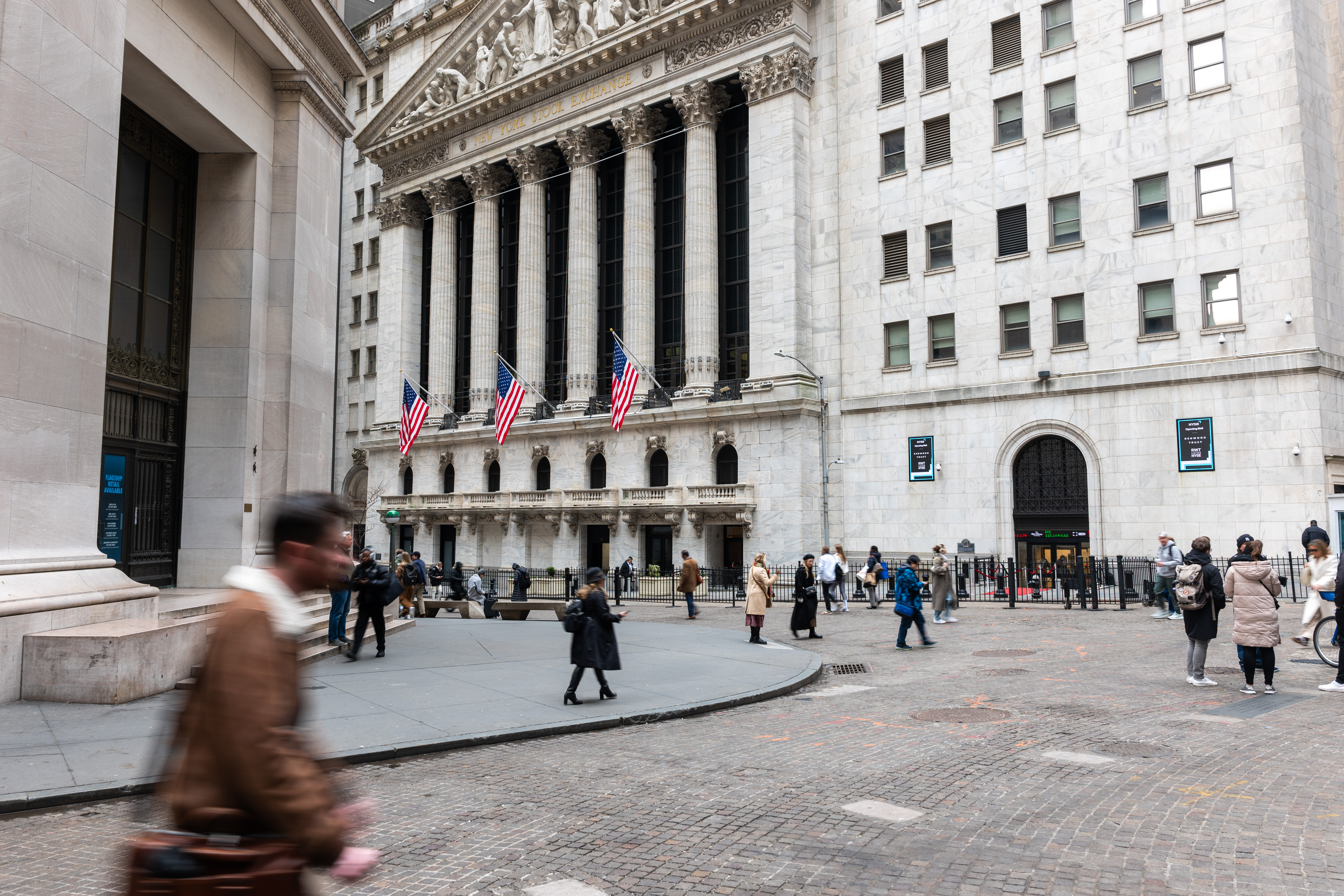 People walk by the New York Stock Exchange on March 20.