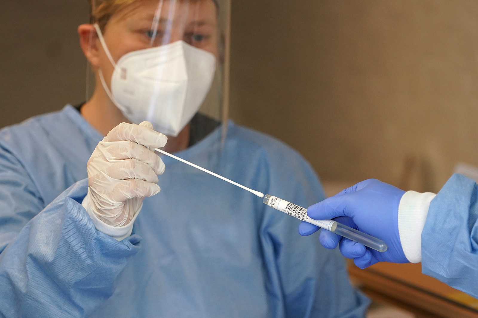 A health care worker places a throat swab sample for Covid-19 into a tube in Berlin on August 7.