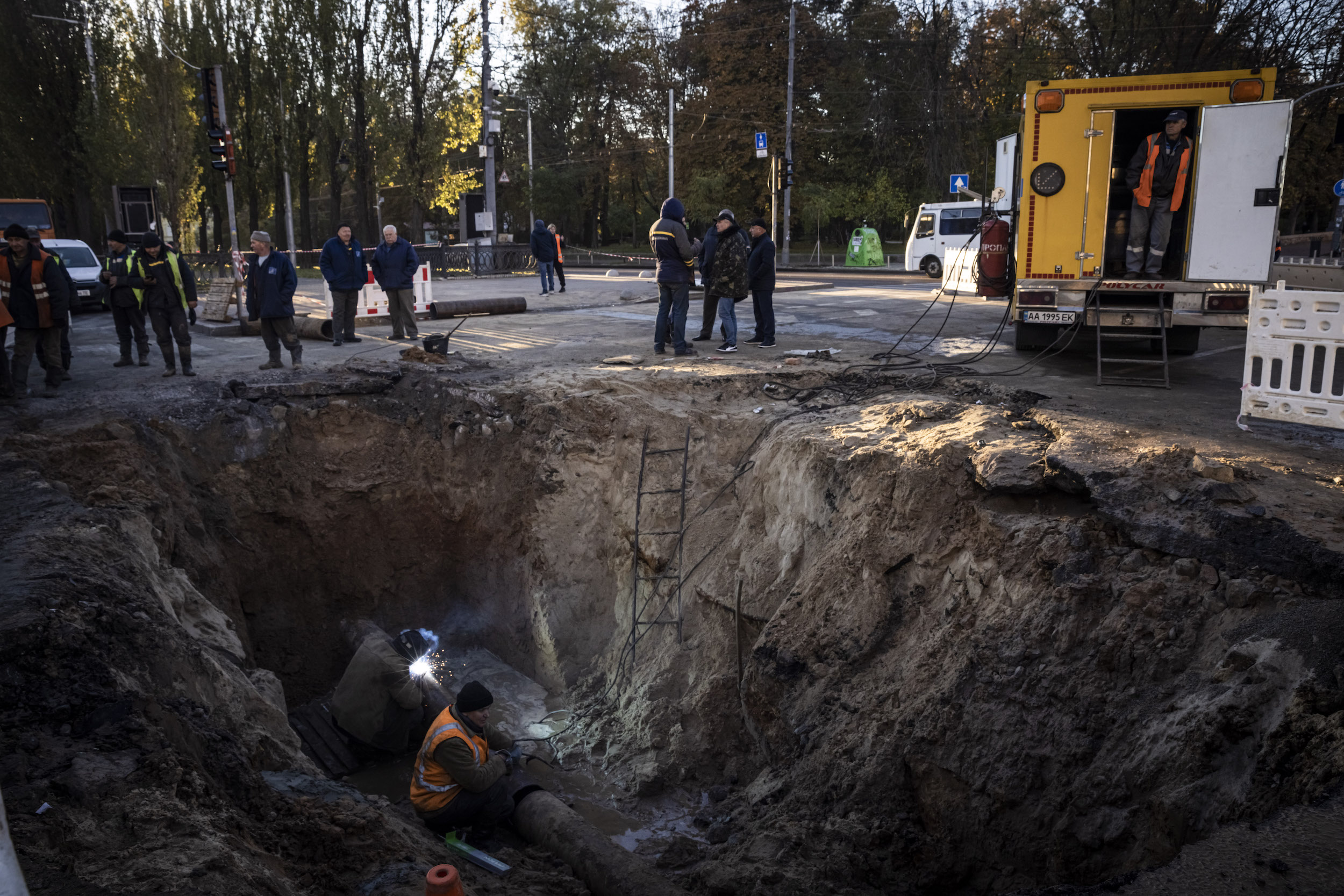 Workers in crater left by a missile strike the day before near Taras Shevchenko National University on October 11, in Kyiv.