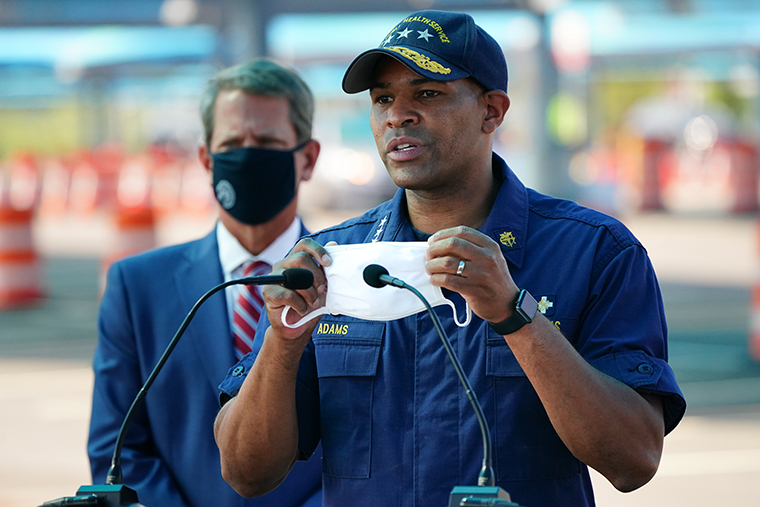U.S. Surgeon General Jerome Adams holds up a mask while speaking as Georgia Governor Brian Kemp looks on during a press conference announcing statewide expanded COVID testing on August 10, 2020 in Atlanta, Georgia. 