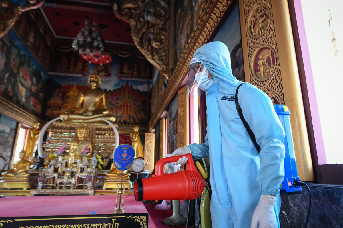 A rescue worker wearing personal protective equipment sprays disinfectant at Klong Toey Nok temple in Bangkok, Thailand on May 16.