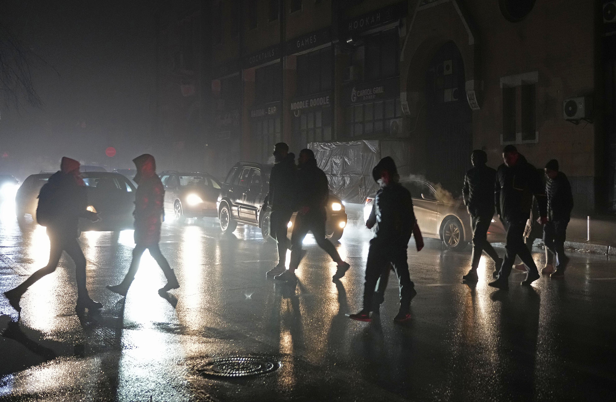 People cross a street in the dark in Kyiv, Ukraine, on November 24, after Russian air strikes caused power outages. 