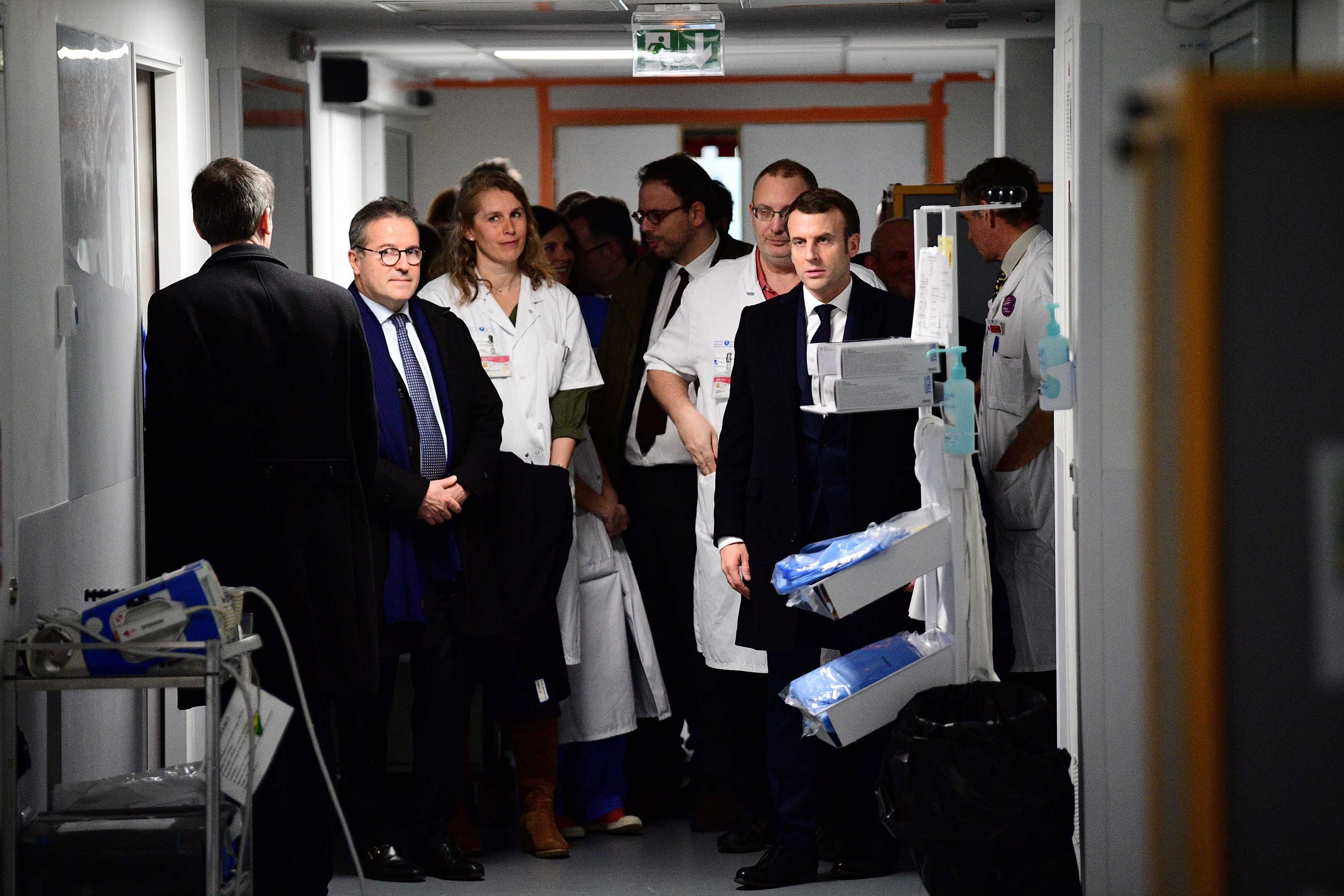 French President Emmanuel Macron, right, visits the Pitié-Salpêtrièr hospital in Paris on Thursday, where the first French victim of the coronavirus died.