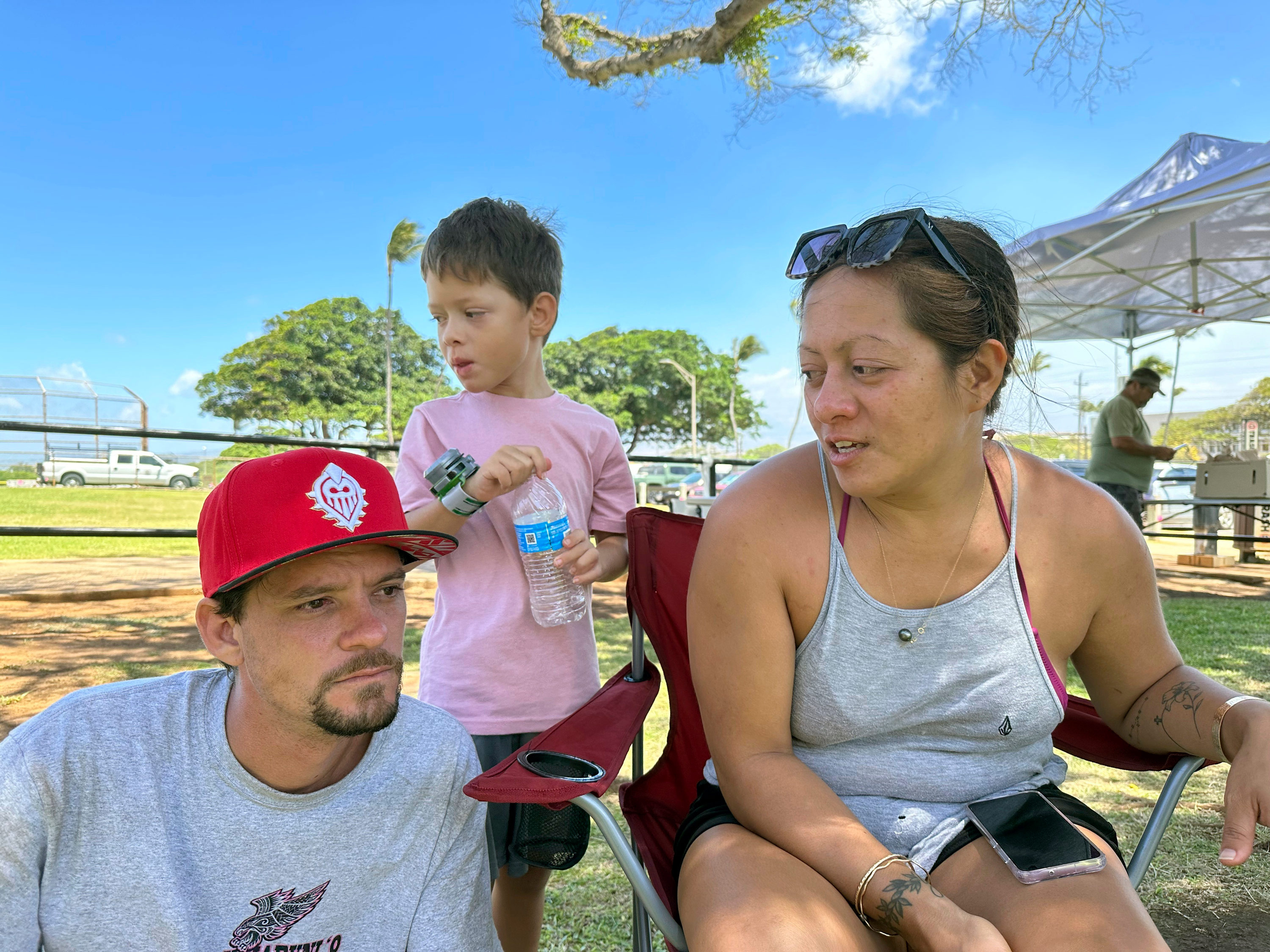 Kamuela Kawaakoa, Iiulia Yasso, and their son Kama, all of Lahaina, rest at an evacuation shelter in Wailuku, Hawaii, on Wednesday, August 9, 2023.