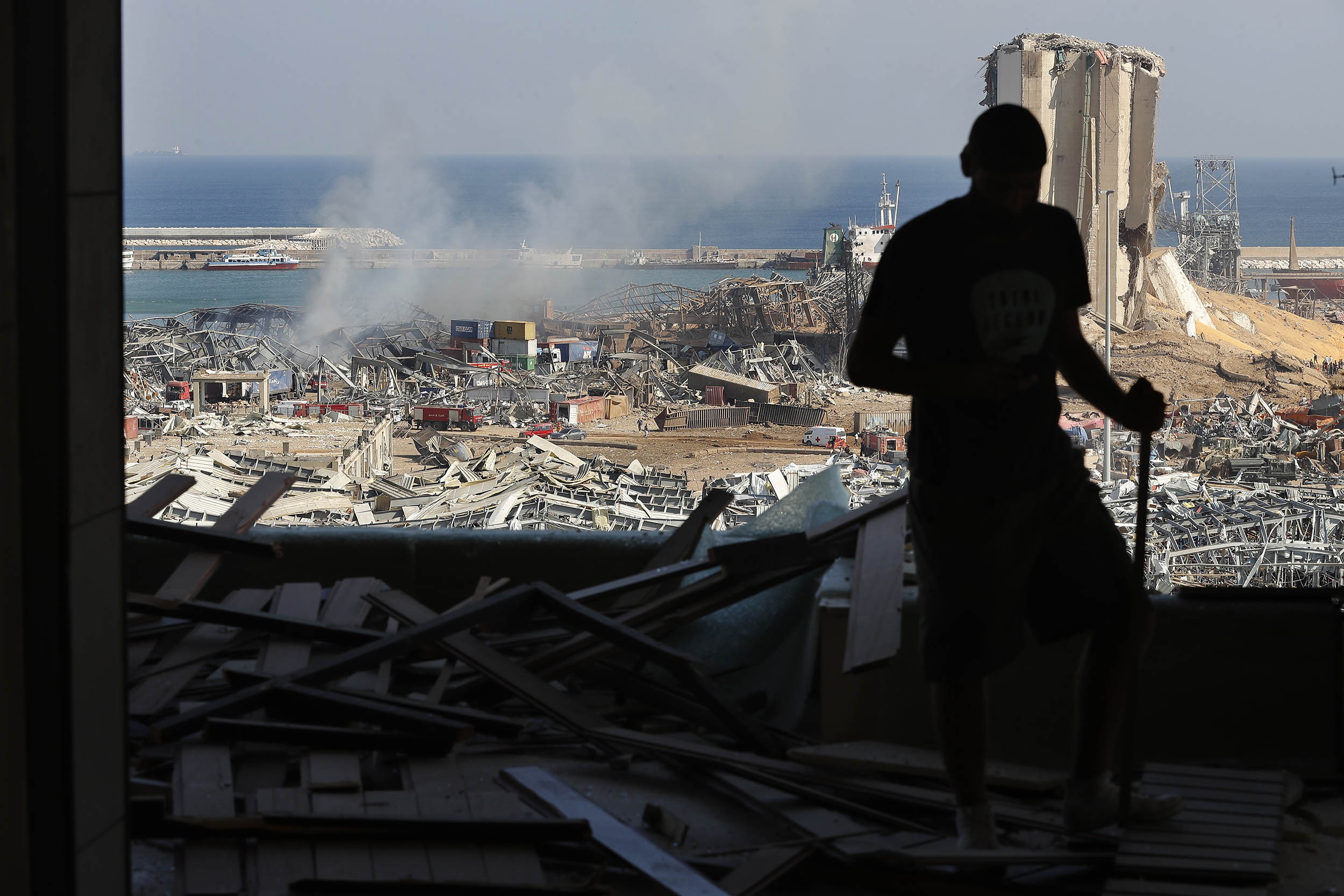 A man stands in a damaged apartment as he looks out at the scene of a massive explosion at the seaport of Beirut, Lebanon, on Wednesday, August 5. 