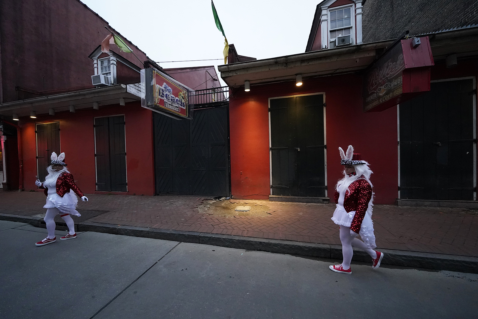People in costume walk past a shuttered bar on Bourbon Street in the French Quarter of New Orleans, on Friday, February 12.