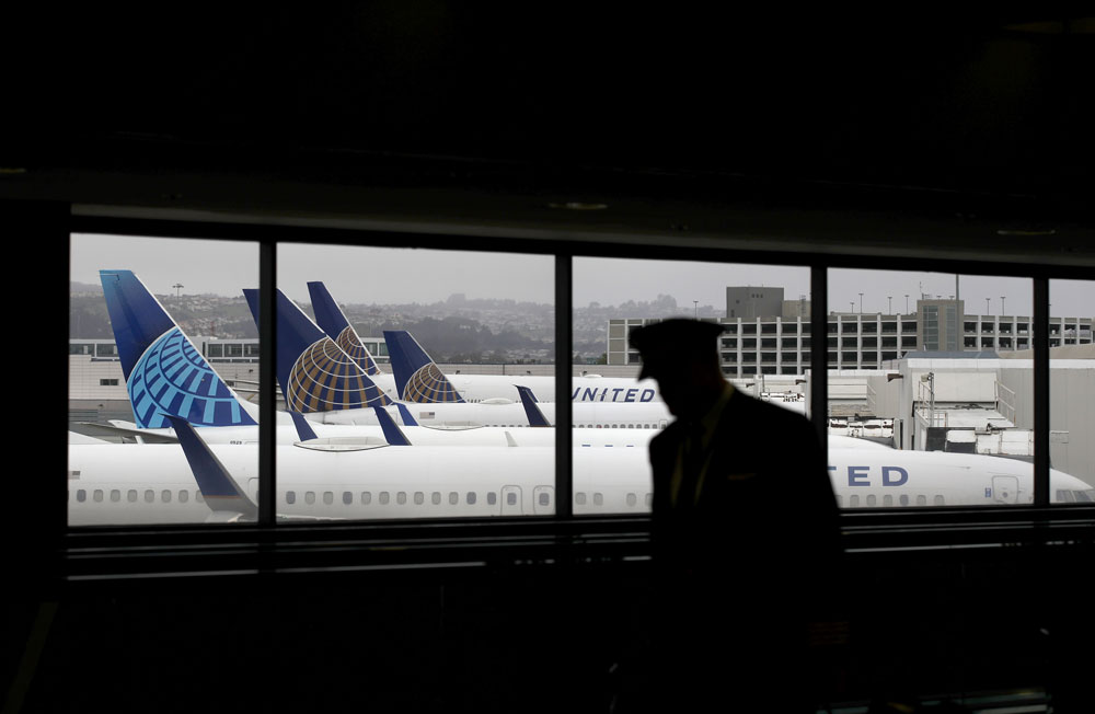 A pilot walks by United Airlines planes as they sit parked at gates at San Francisco International Airport on April 12 in San Francisco. 