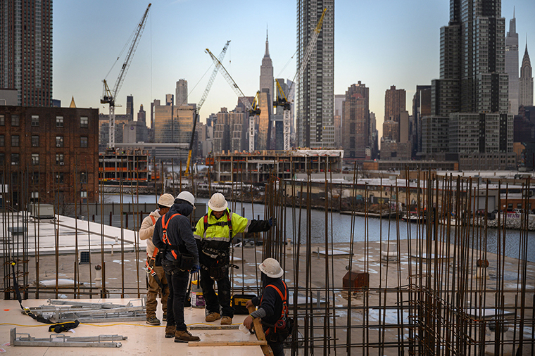 A general view shows construction workers standing before the Manhattan skyline and Empire State Building, in Brooklyn, NY, on January 24.