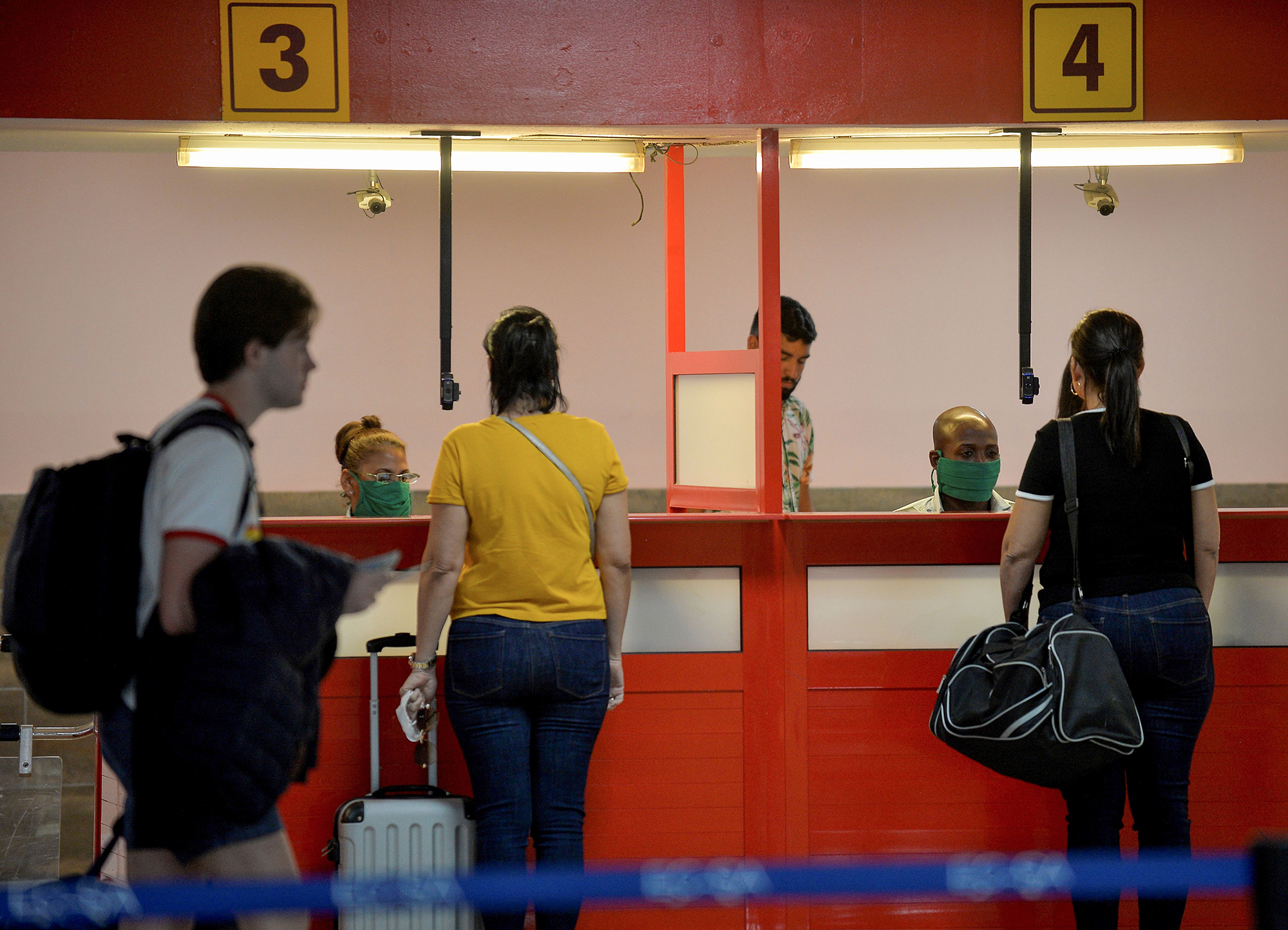Airport workers wearing face masks attend tourists at the Jose Marti International Airport in Havana, on March 13.