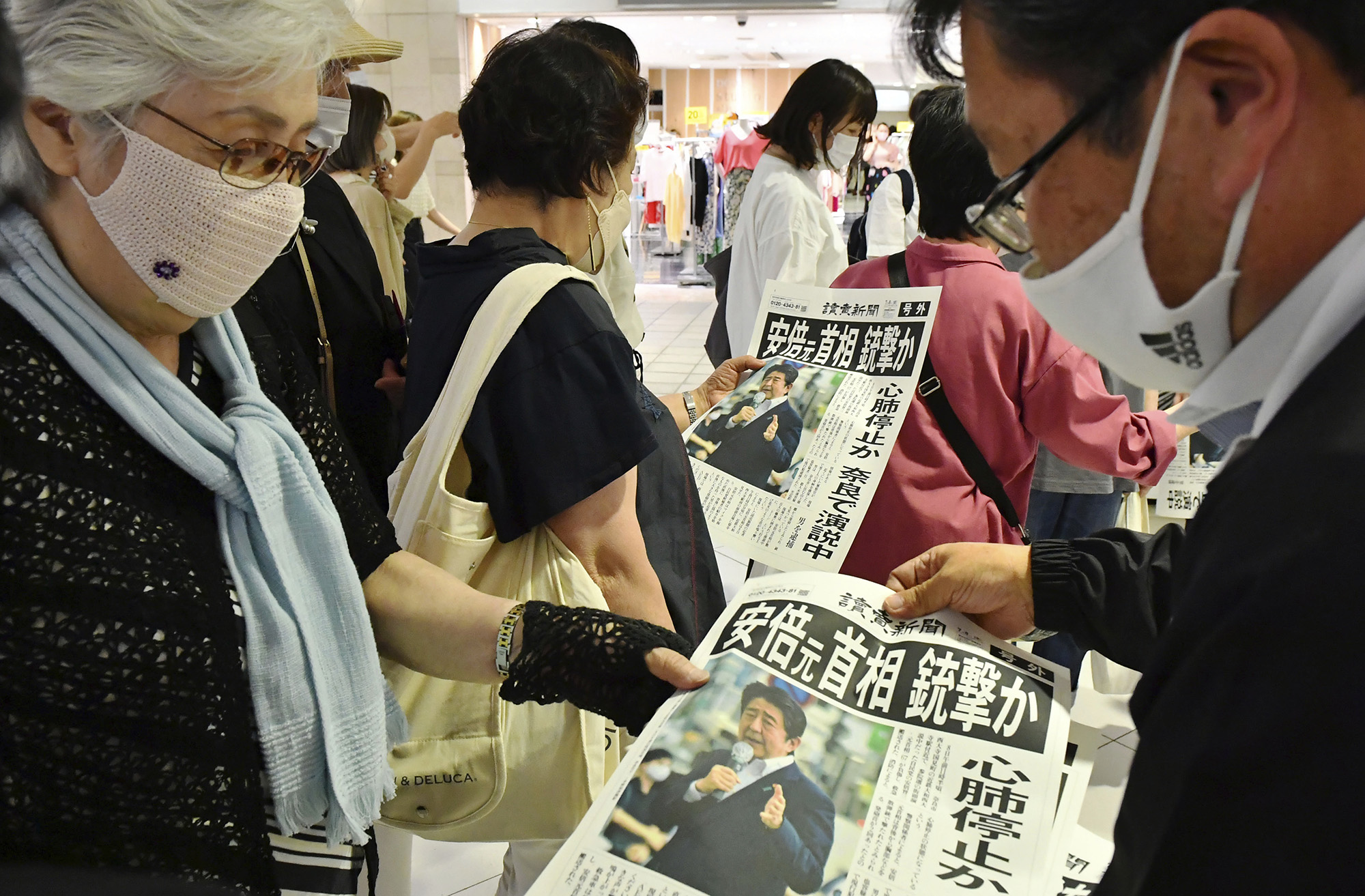 Passersby pick up an extra edition of the Yomiuri Shimbun newspaper in in Sapporo, Hokkaido Prefecture on July 8 after Japan's former Prime Minister Shinzo Abe was shot.