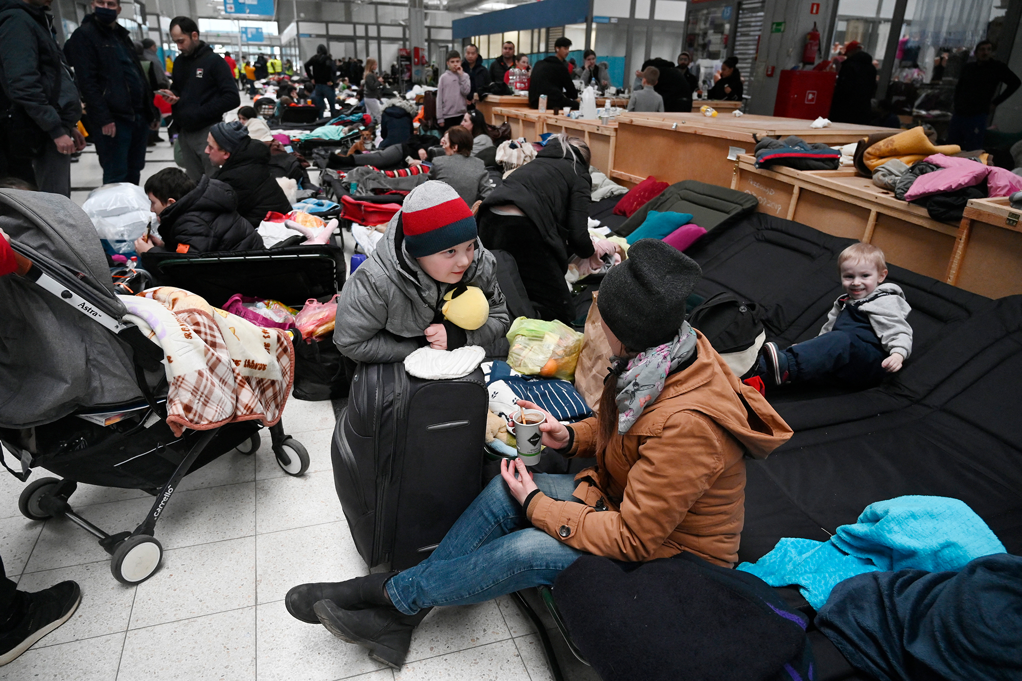 Le persone si siedono sui lettini da campo presso il centro di accoglienza dei rifugiati a Kortzowa, in Polonia, il 5 marzo. 