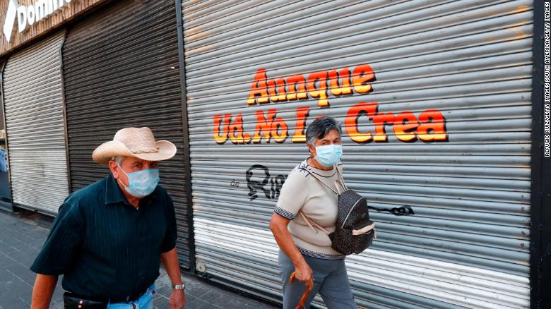 People walk by a closed store during the pandemic in Guadalajara City, Mexico.
