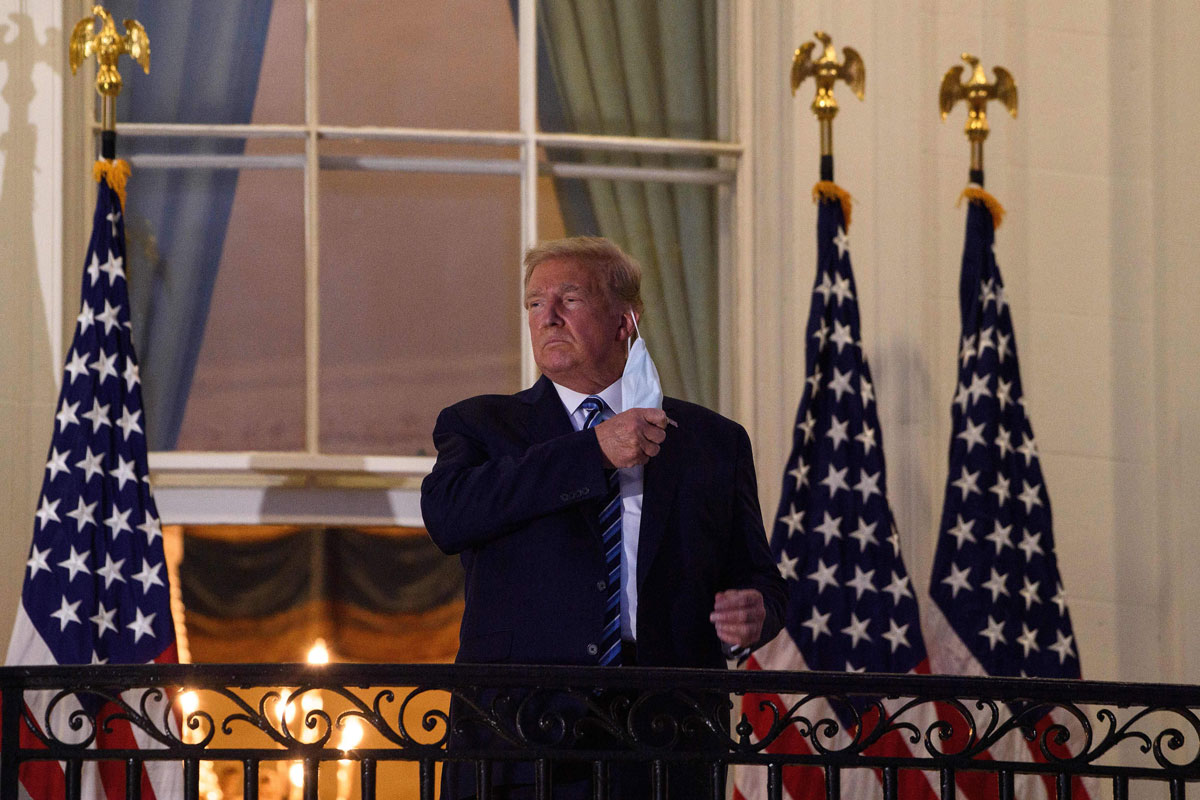 President Donald Trump takes off his face mask as he arrives at the White House upon his October 5 return from Walter Reed Medical Center, where he underwent treatment for Covid-19.