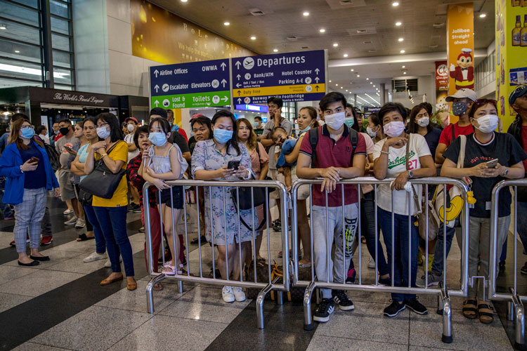 Greeters wearing face masks wait for arriving travelers at the arrival area of Ninoy Aquino International Airport on March 10, in Manila, Philippines.