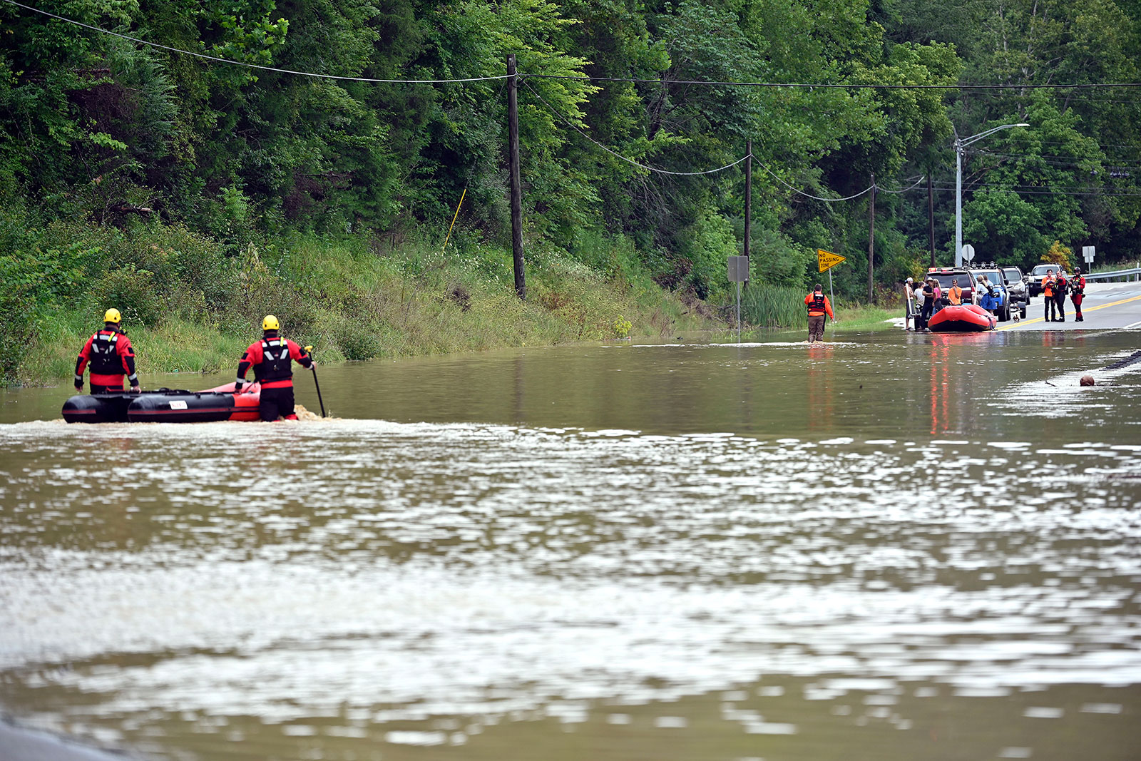 Members of the Winchester, Kentucky, Fire Department walk inflatable boats across flood waters over Kentucky State Road 15 in Jackson, Kentucky, to pick up people stranded on Thursday, July 28.