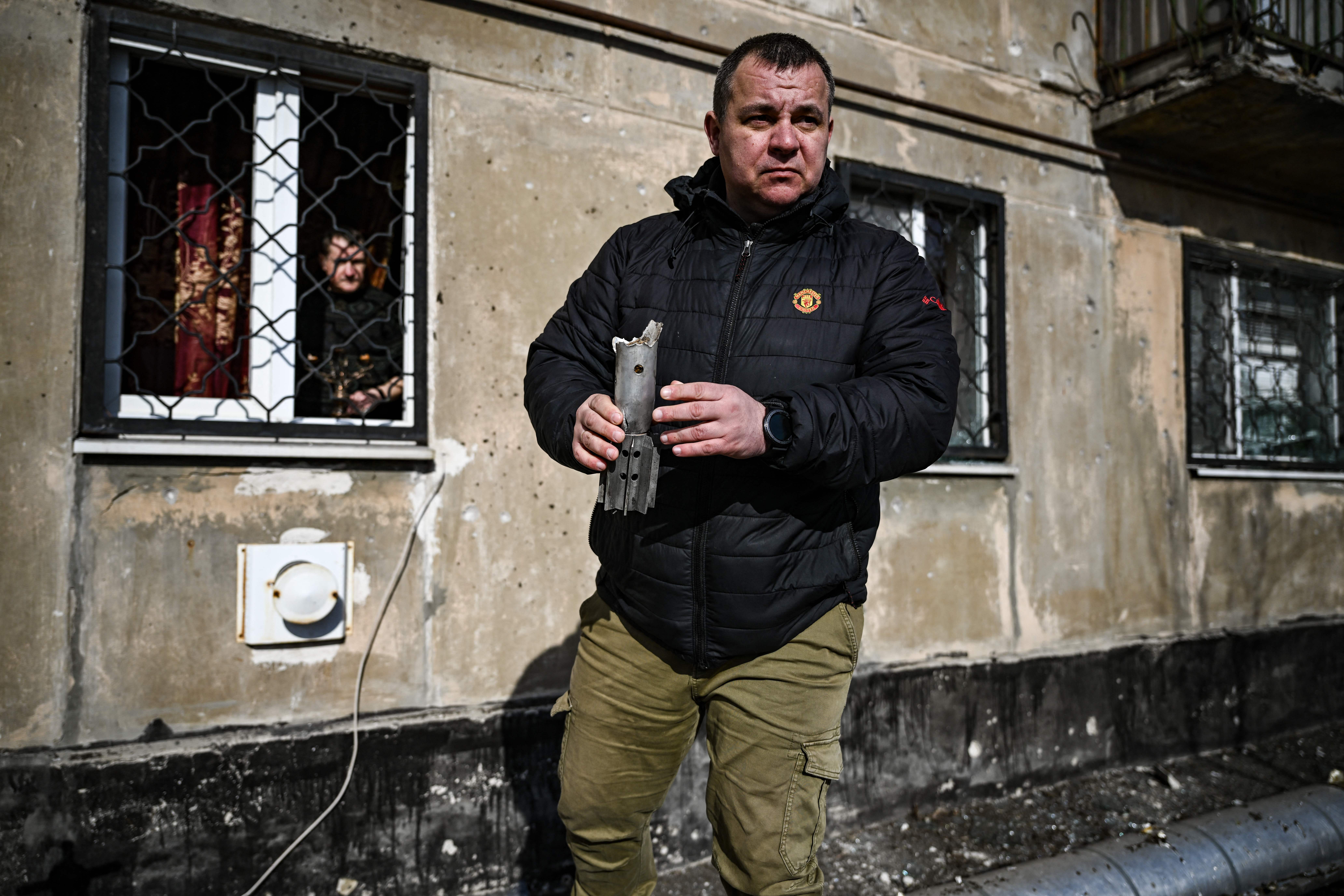 A man holds the remains of a mortar which exploded in front of a building in the town of Schastia, Ukraine, on February 22.