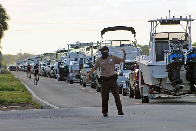A Miami-Dade police officer directs traffic on May 2, as hundreds of cars and trucks hauling boats lined up waiting to get into Blackpoint Marina in Homestead, Florida. 