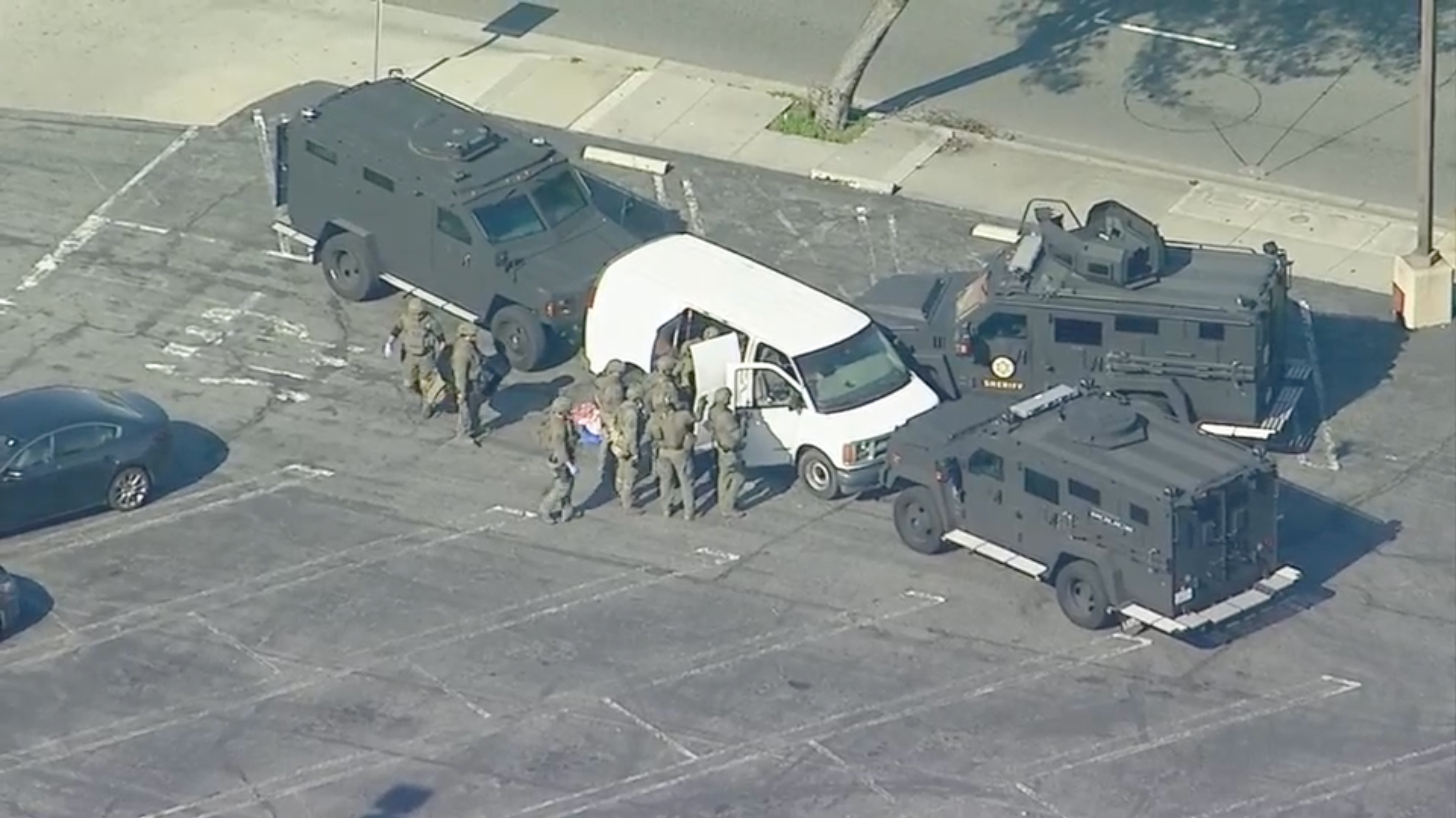 A tactical team searches a white cargo van during a standoff with officers in Torrance, California on Sunday.