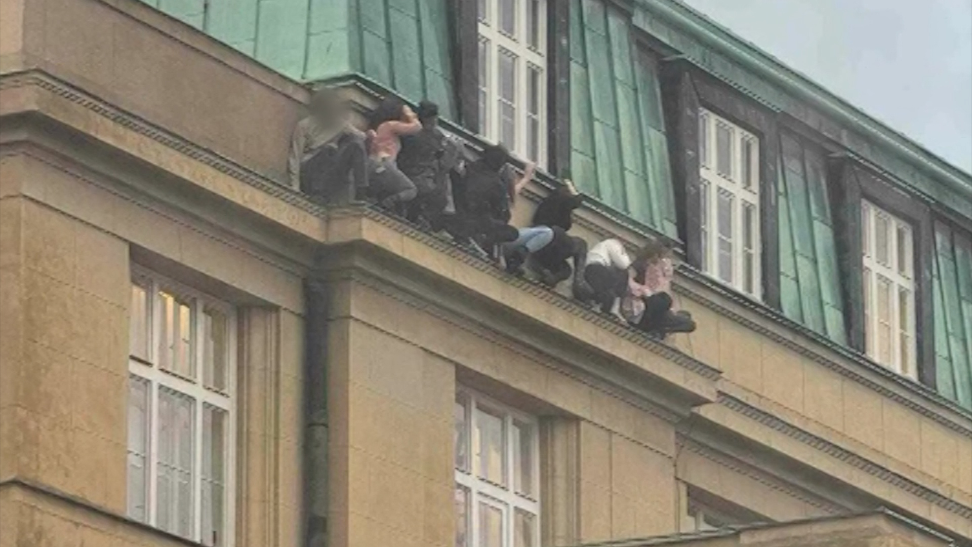 Students are seen hiding on a ledge at Charles University. A portion of this photo has been blurred by CNN to protect identity.